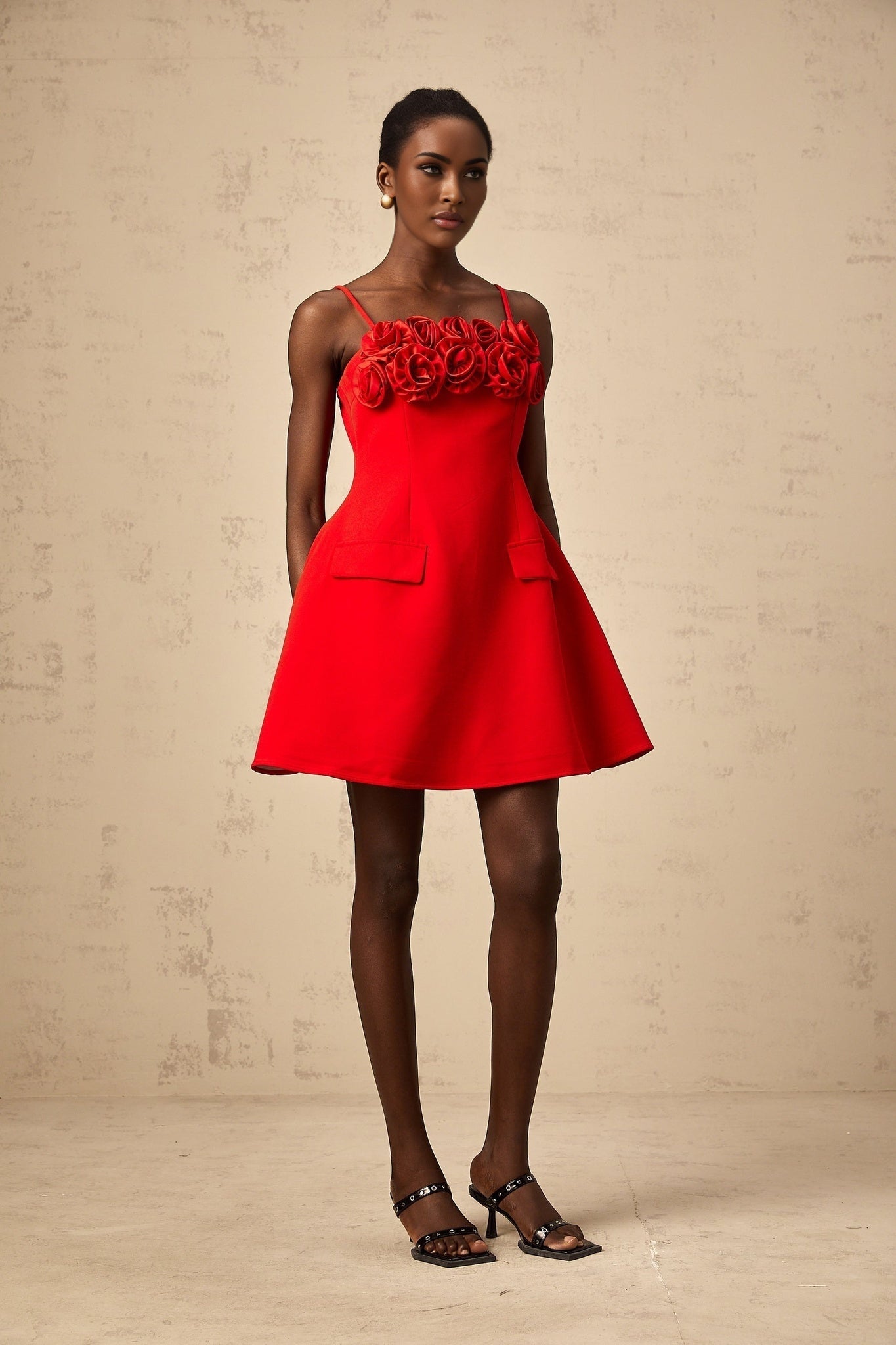 A red mini dress with a flared skirt featuring rose appliqués and a fitted bodice