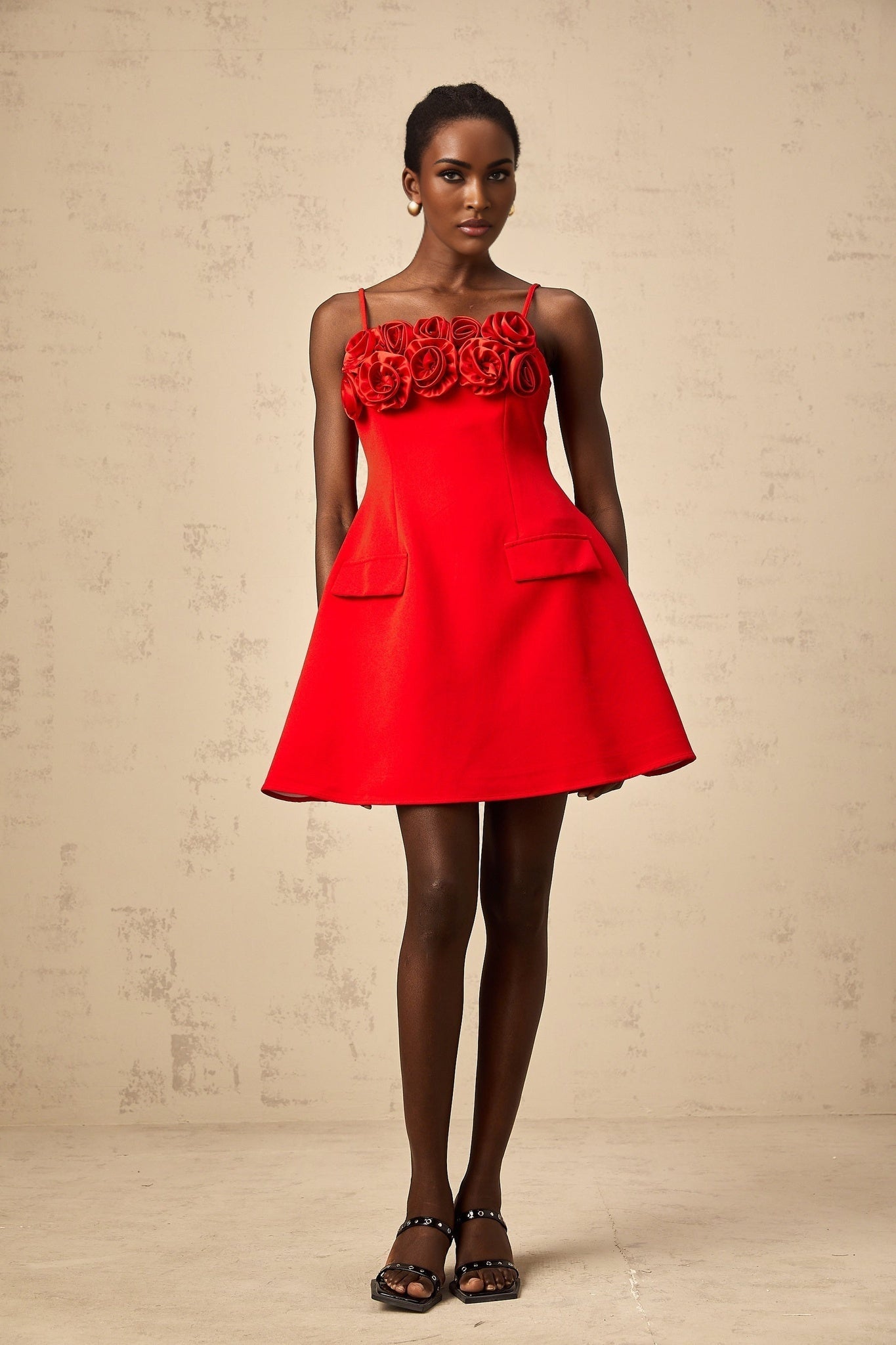 A red mini dress with a flared skirt featuring rose appliqués and a fitted bodice
