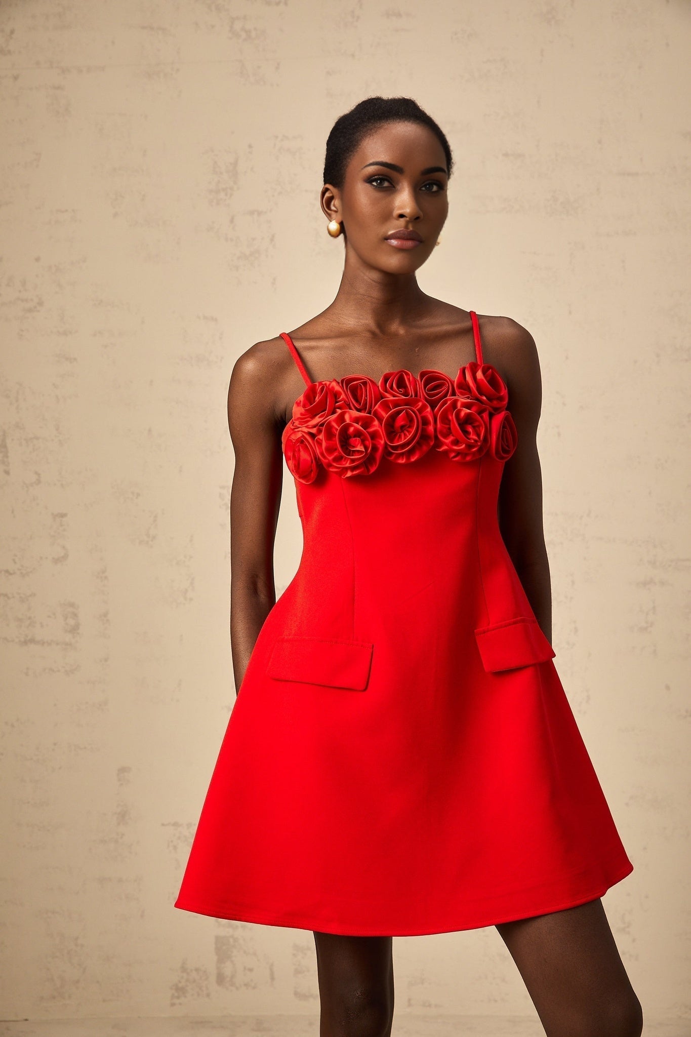 A red mini dress with a flared skirt featuring rose appliqués and a fitted bodice