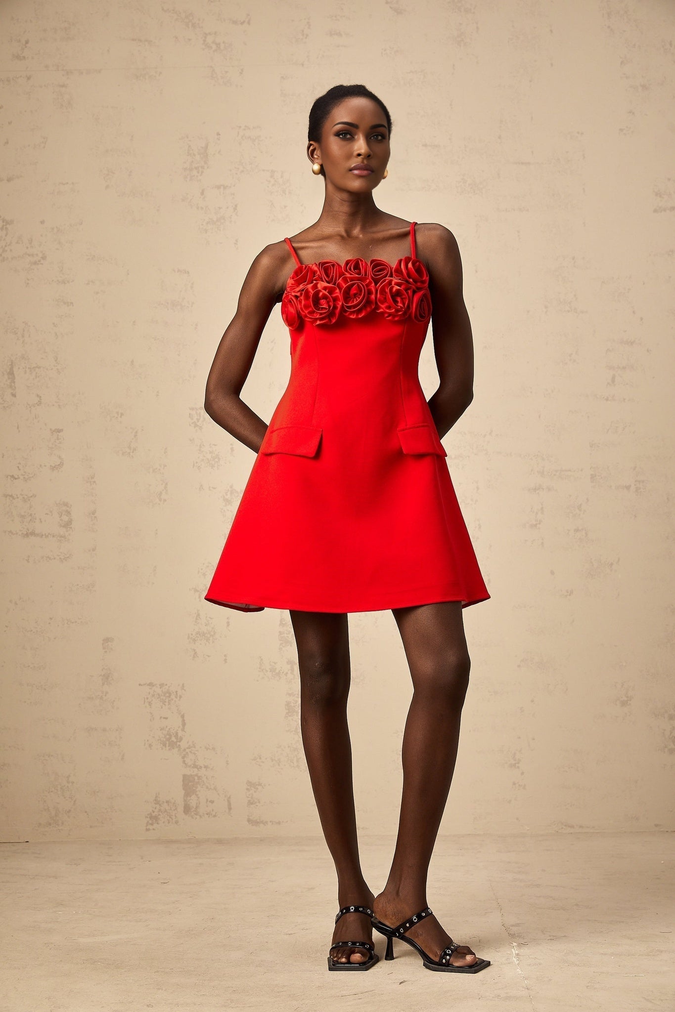 A red mini dress with a flared skirt featuring rose appliqués on the bodice