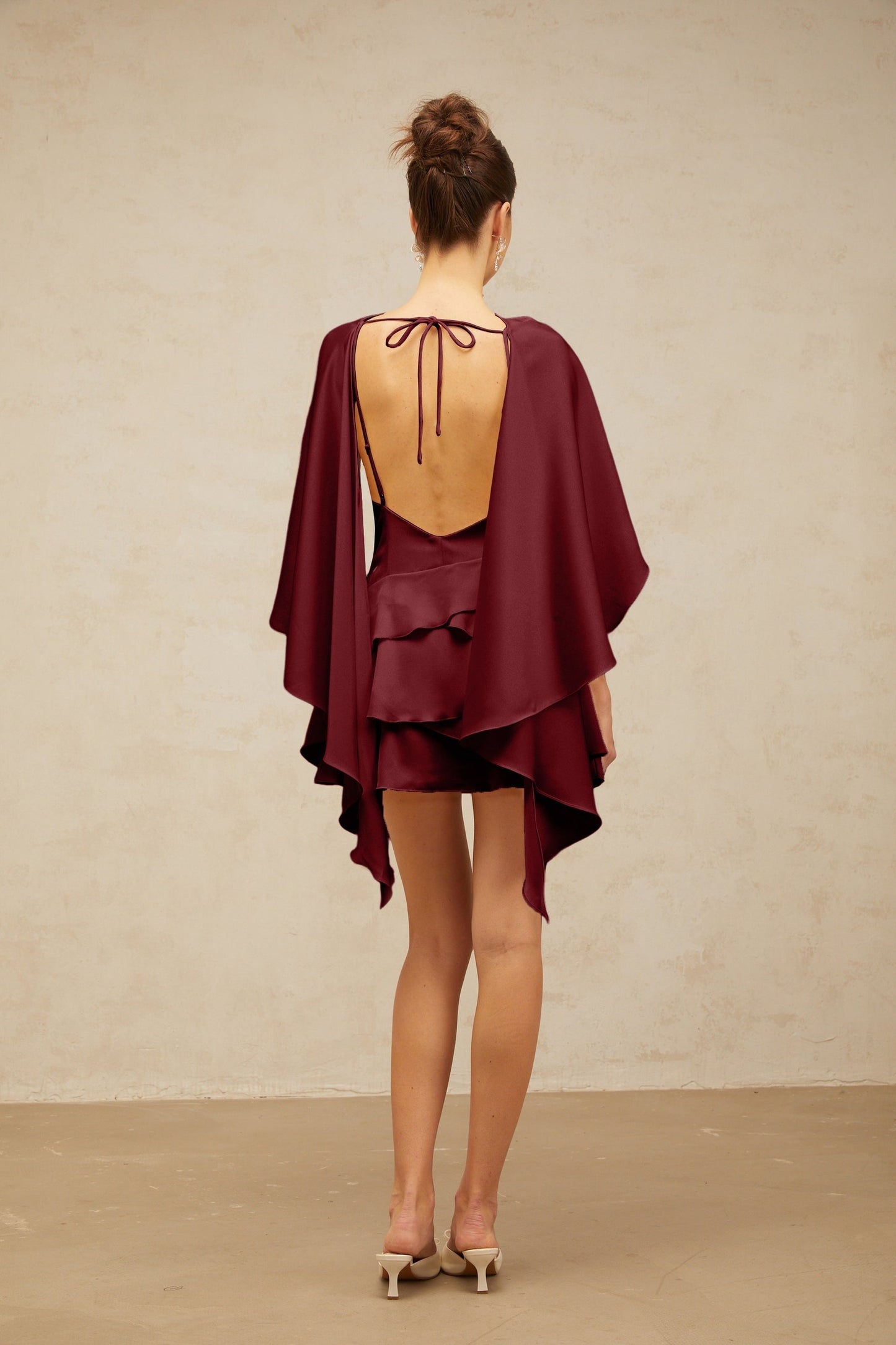 A red satin mini dress with a shawl panel and ruffled details featuring a short length and feminine silhouette