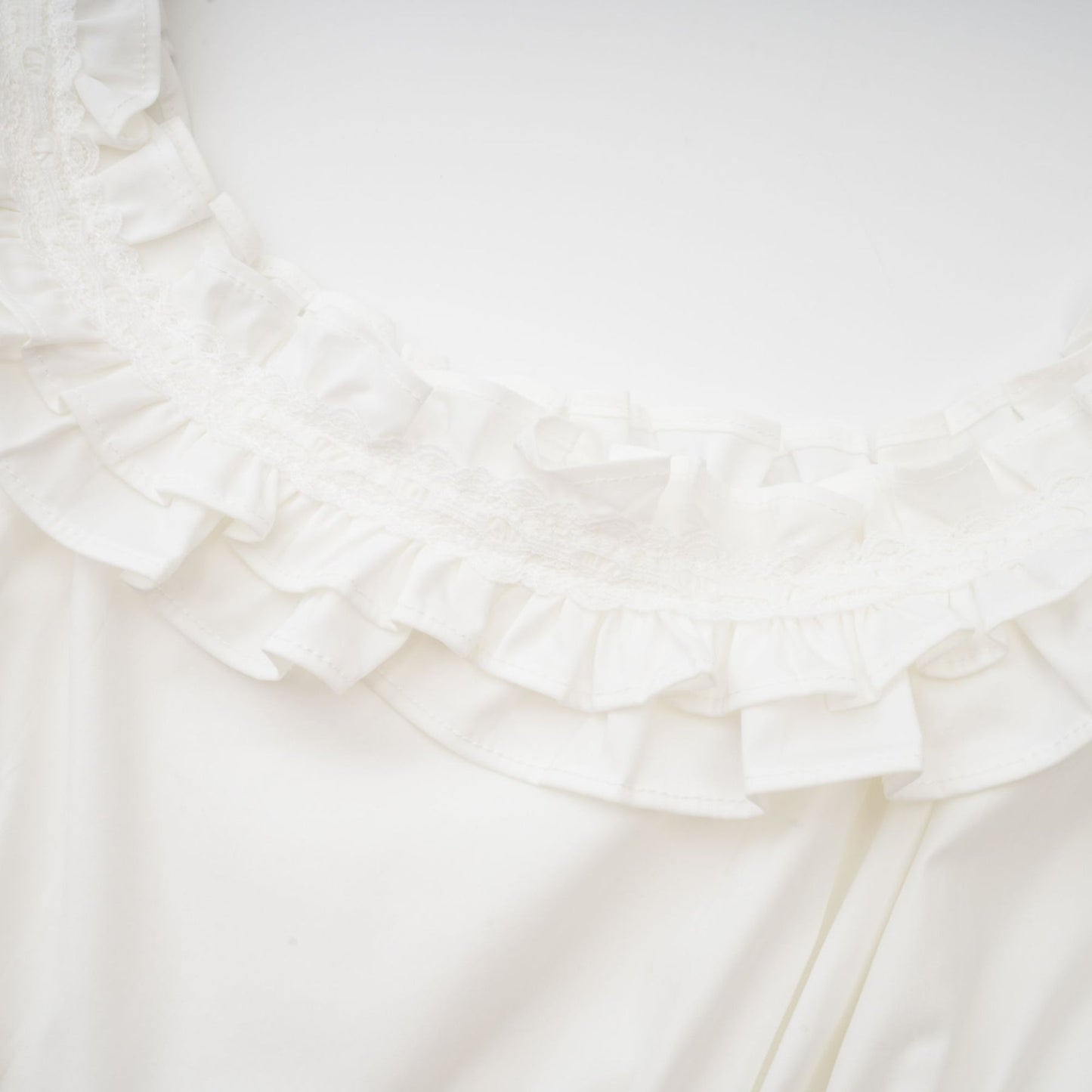 A white cotton dress with a Uneck ruffled detailing crystal embellishments and pleats