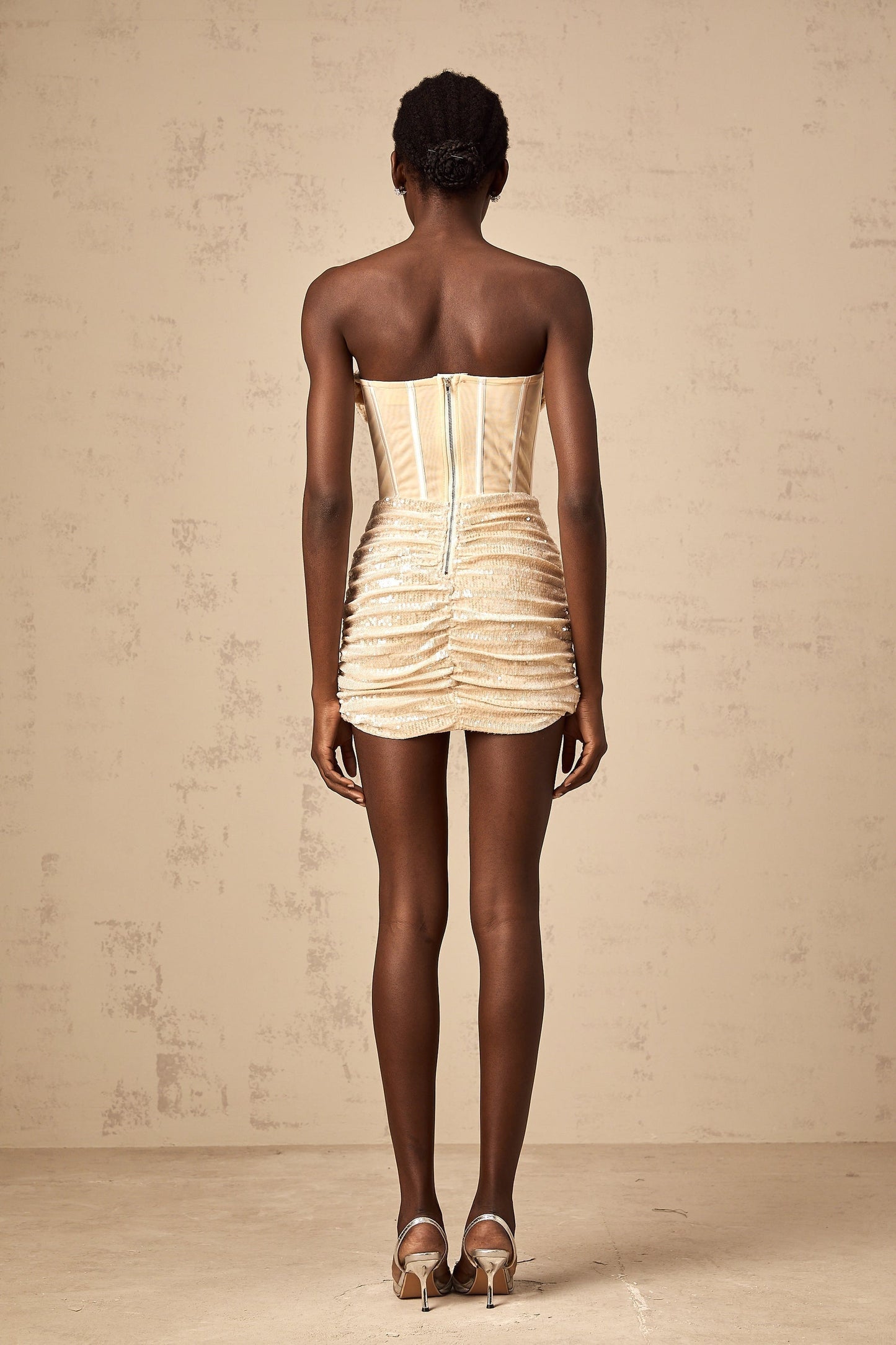 A short beige tulle mini dress with allover sequin embellishment and a sleeveless design featuring a fitted silhouette and scoop neckline