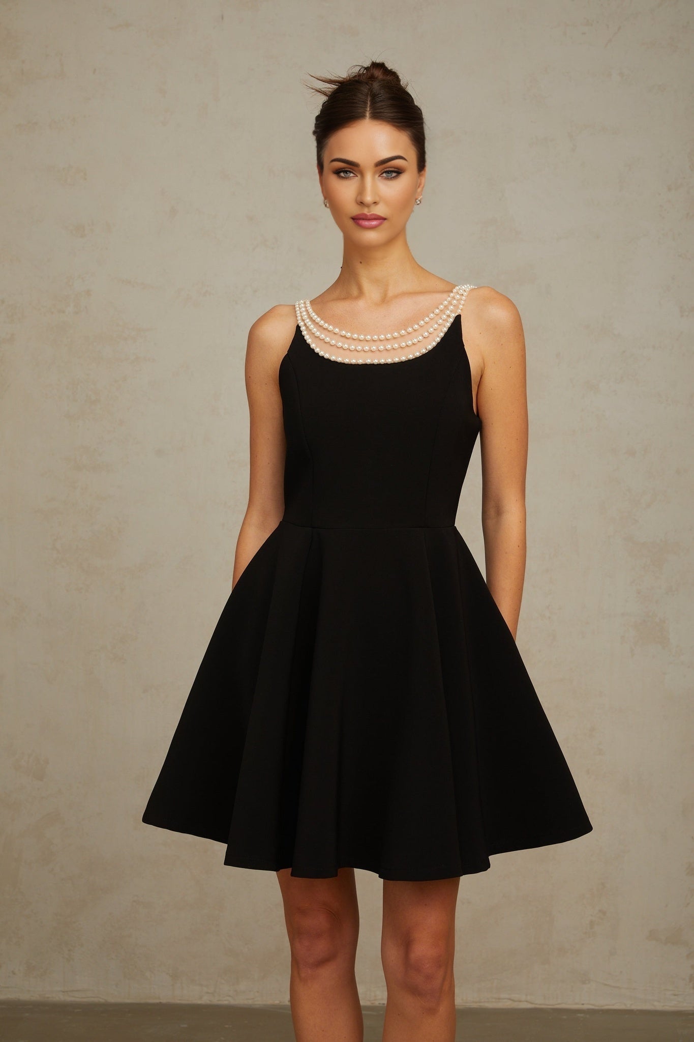 A short black mini dress adorned with faux pearl embellishments named Danae