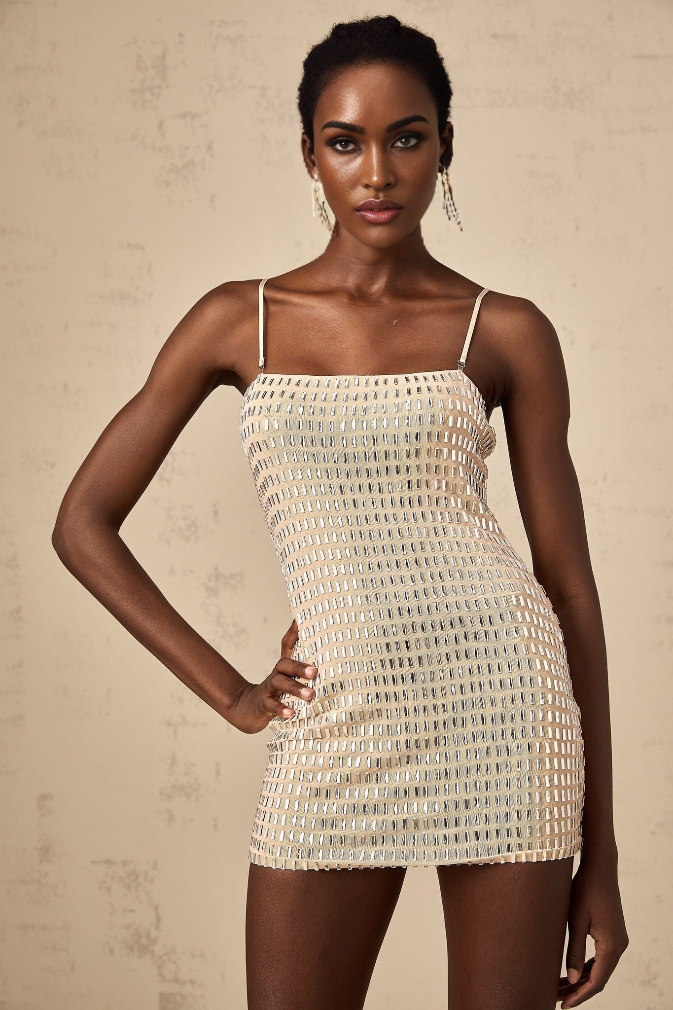 A short black mini dress with shiny stud embellishments covering the fabric creating a textured and glamorous look