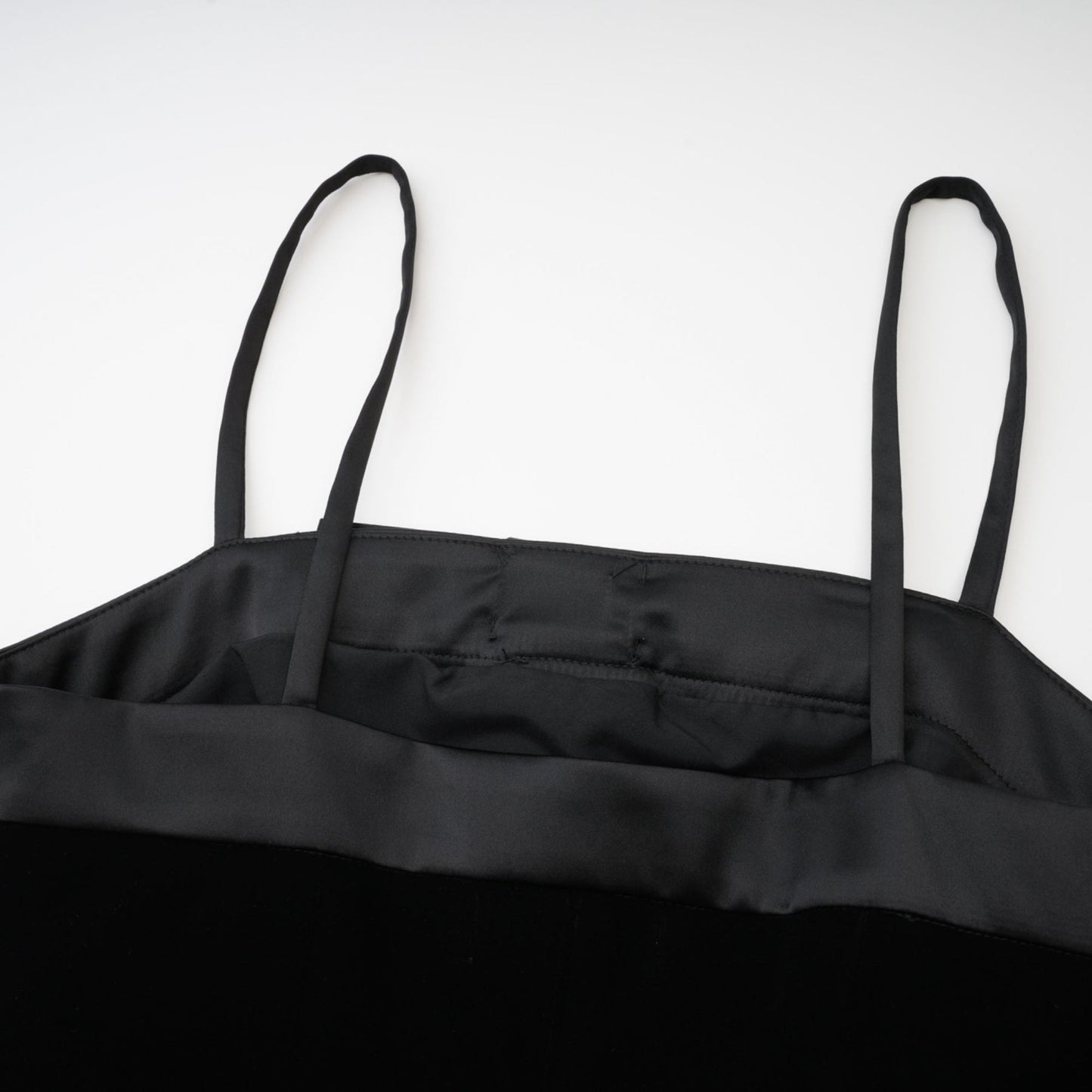 A black sleeveless dress with spaghetti straps bow detail decorative button and side zip made of 65% viscose and 35% Cupro