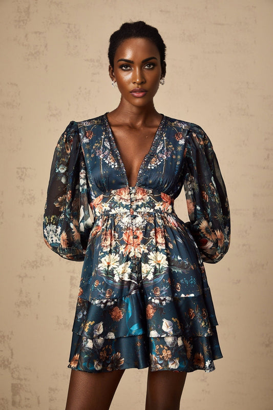 A short blue mini dress with a graphic print pattern and embellishments worn by a model named Candice