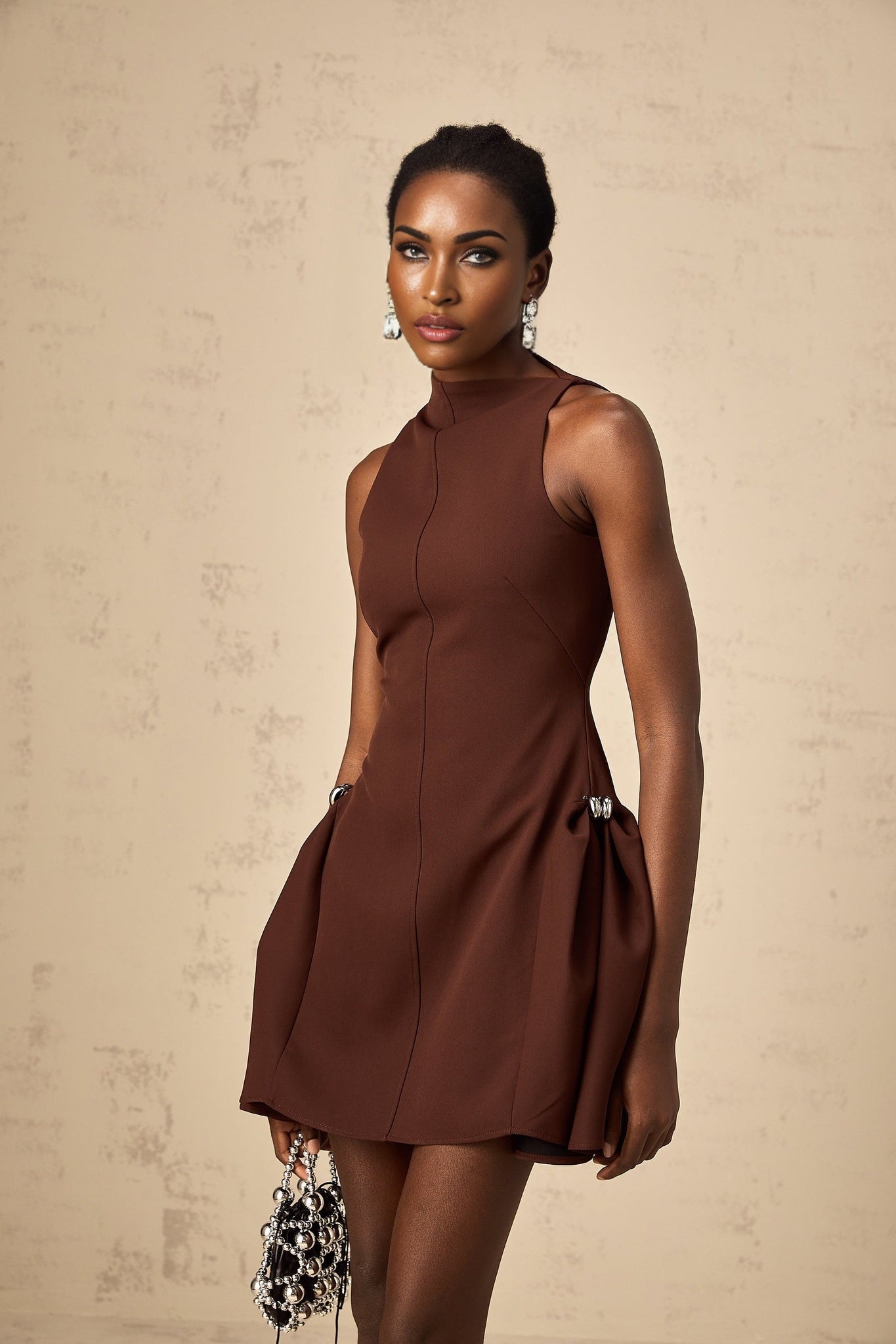 A short brown dress with an asymmetric neckline and puff sleeves featuring a mini length and a fitted silhouette named Dora
