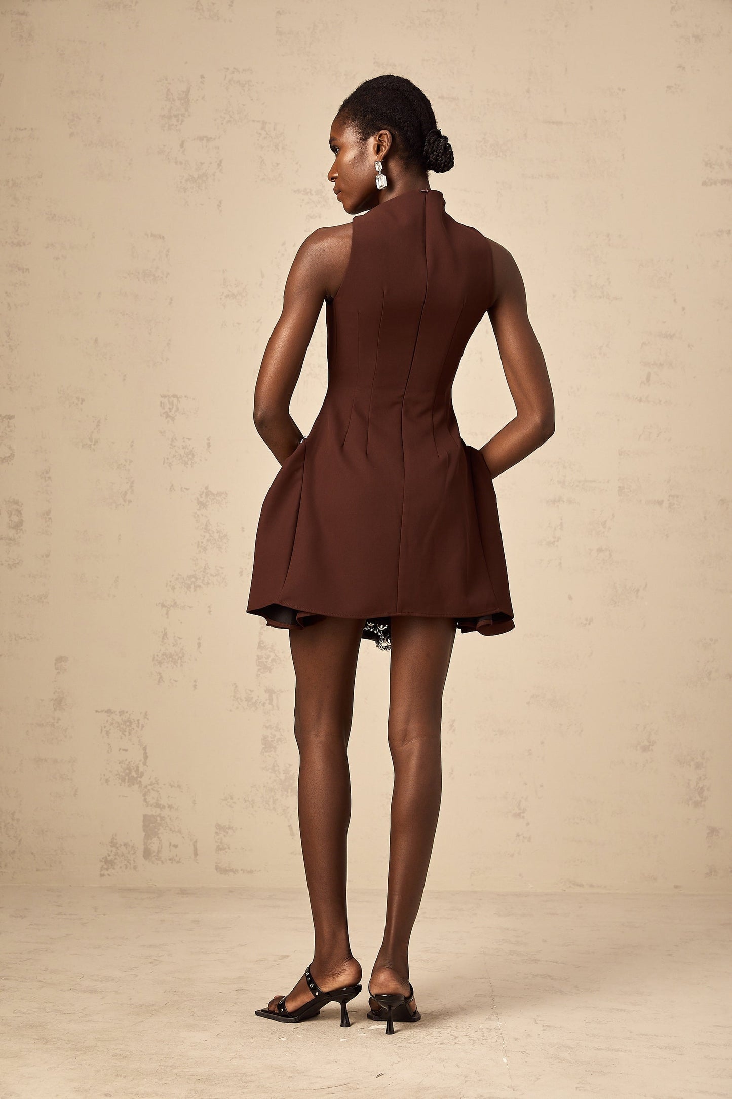 A short brown dress with an asymmetric neckline and puff sleeves in a mini length featuring a Dora design