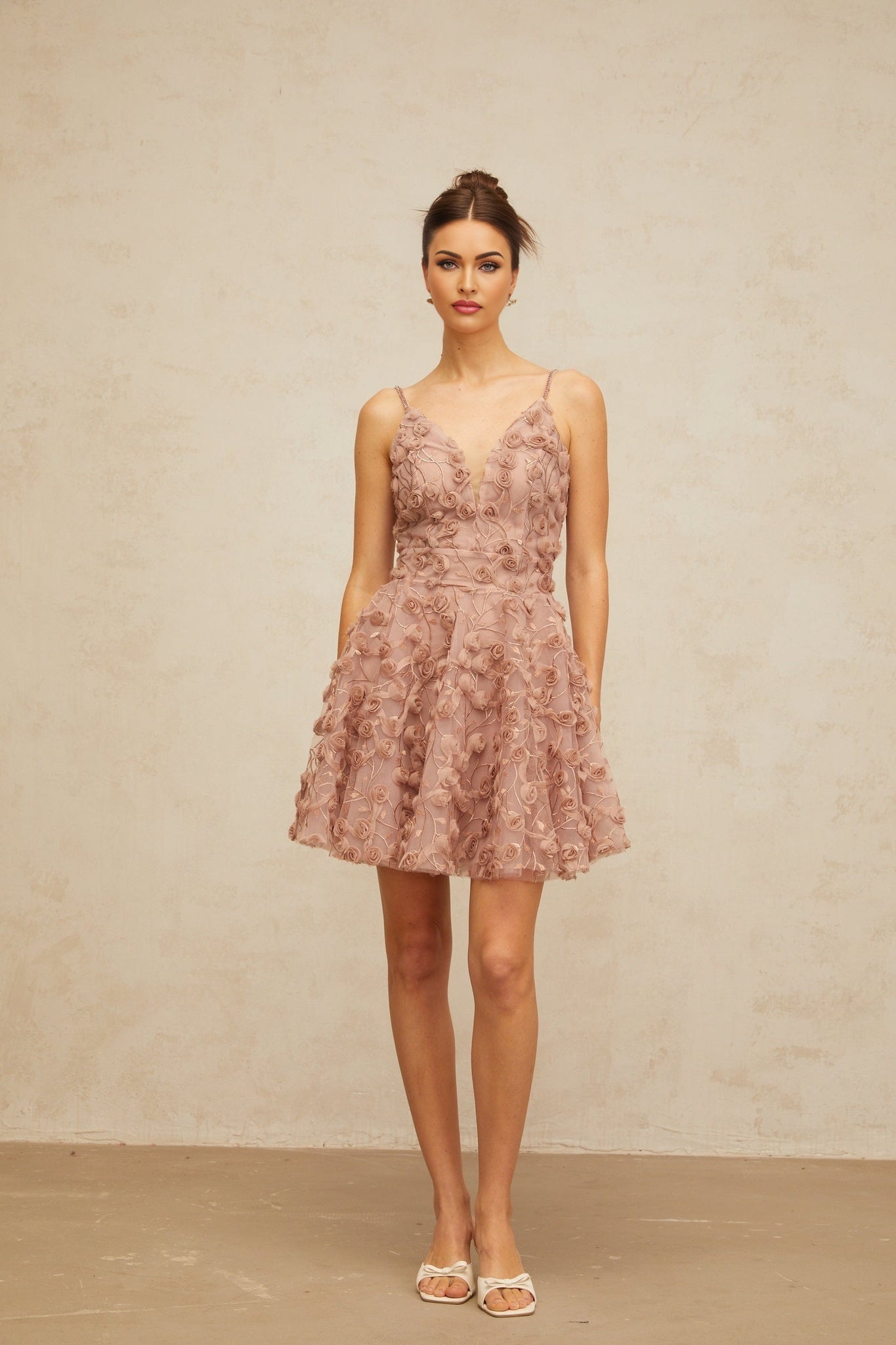 A short dusty pink mini dress with flounced hem featuring rose appliques scattered across the fabric