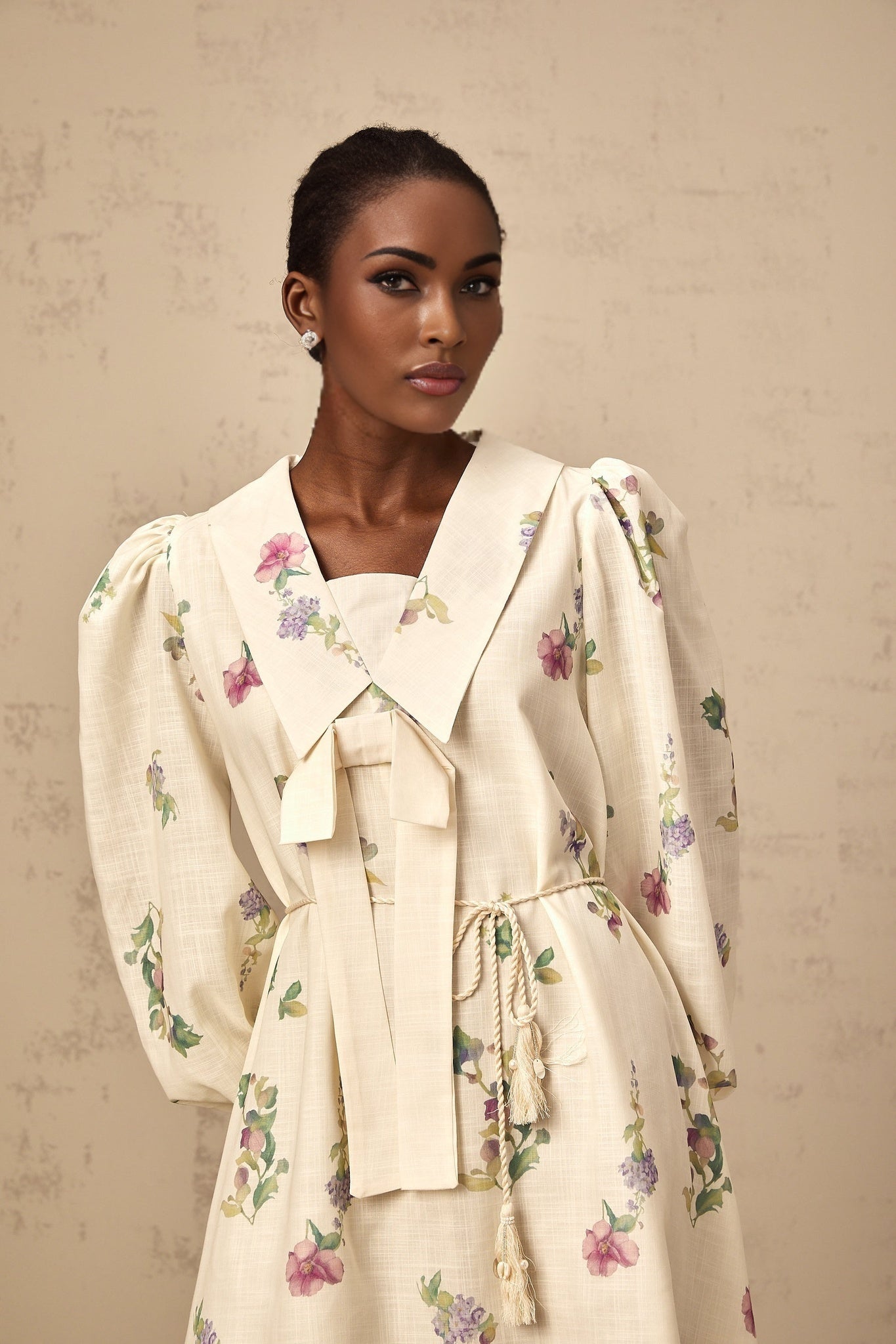 A short floral print mini dress in neutral colors featuring a bow detail