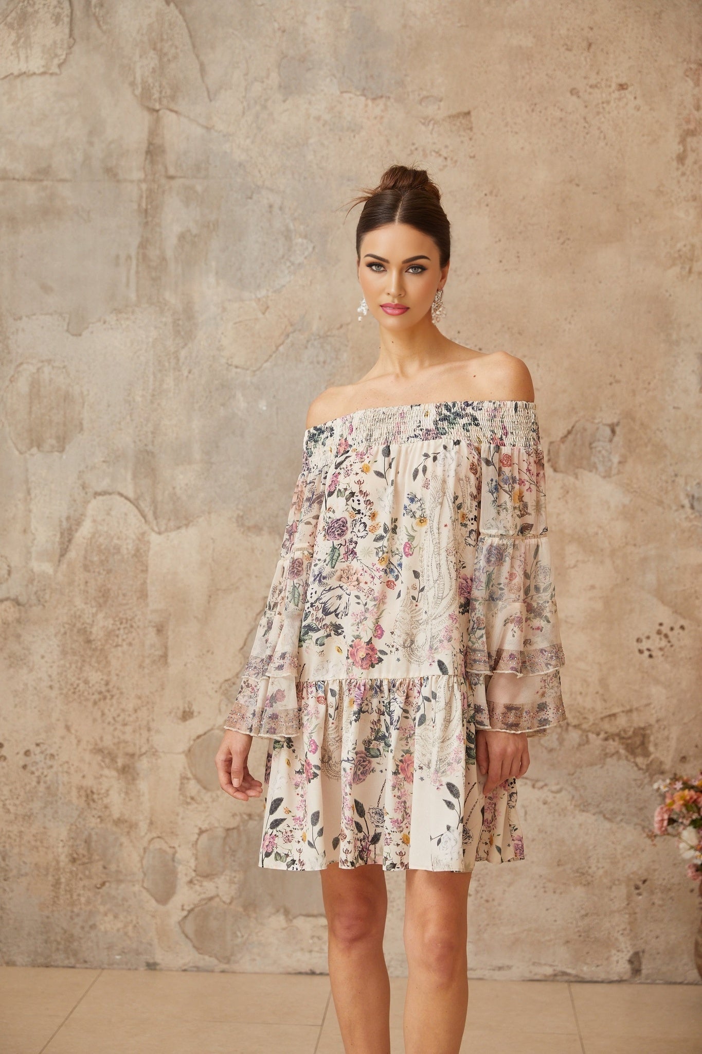 A short floral print mini dress with smocked detailing called Yasmine featuring a colorful floral pattern on a light background with gathered fabric and a fitted waist