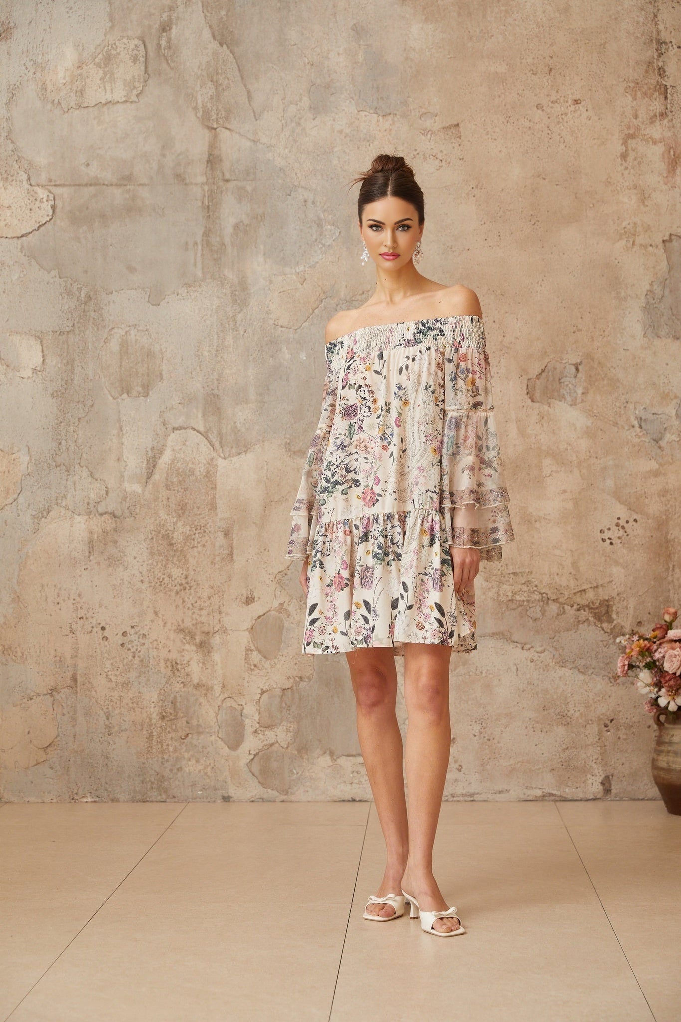 A short floral print mini dress with smocked detailing named Yasmine featuring a vibrant pattern on a light background