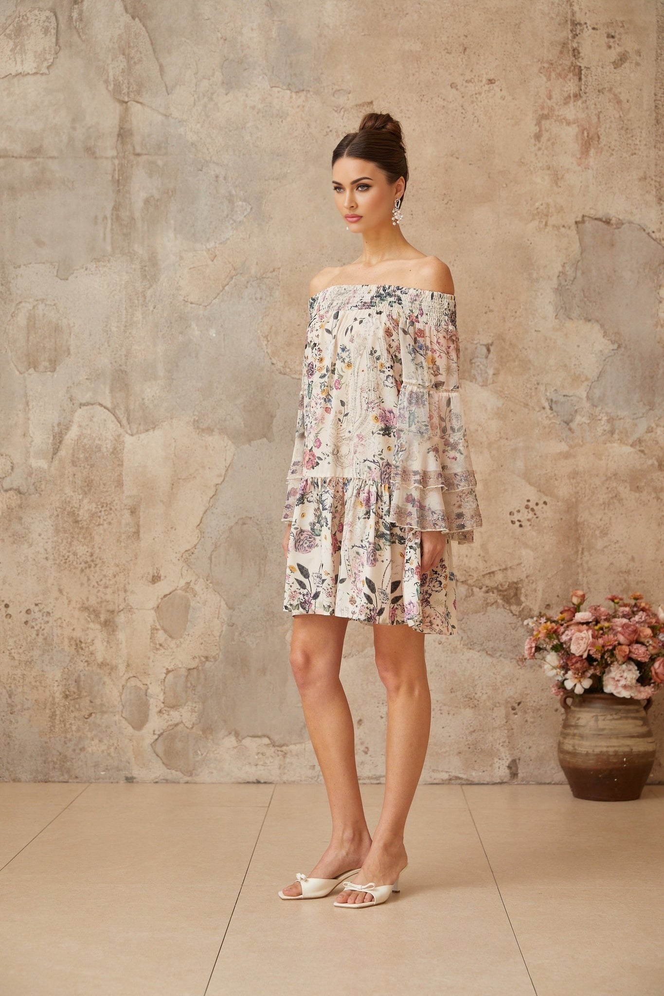 A short floral print mini dress with smocked details called Yasmine featuring a vibrant pattern and fitted waist