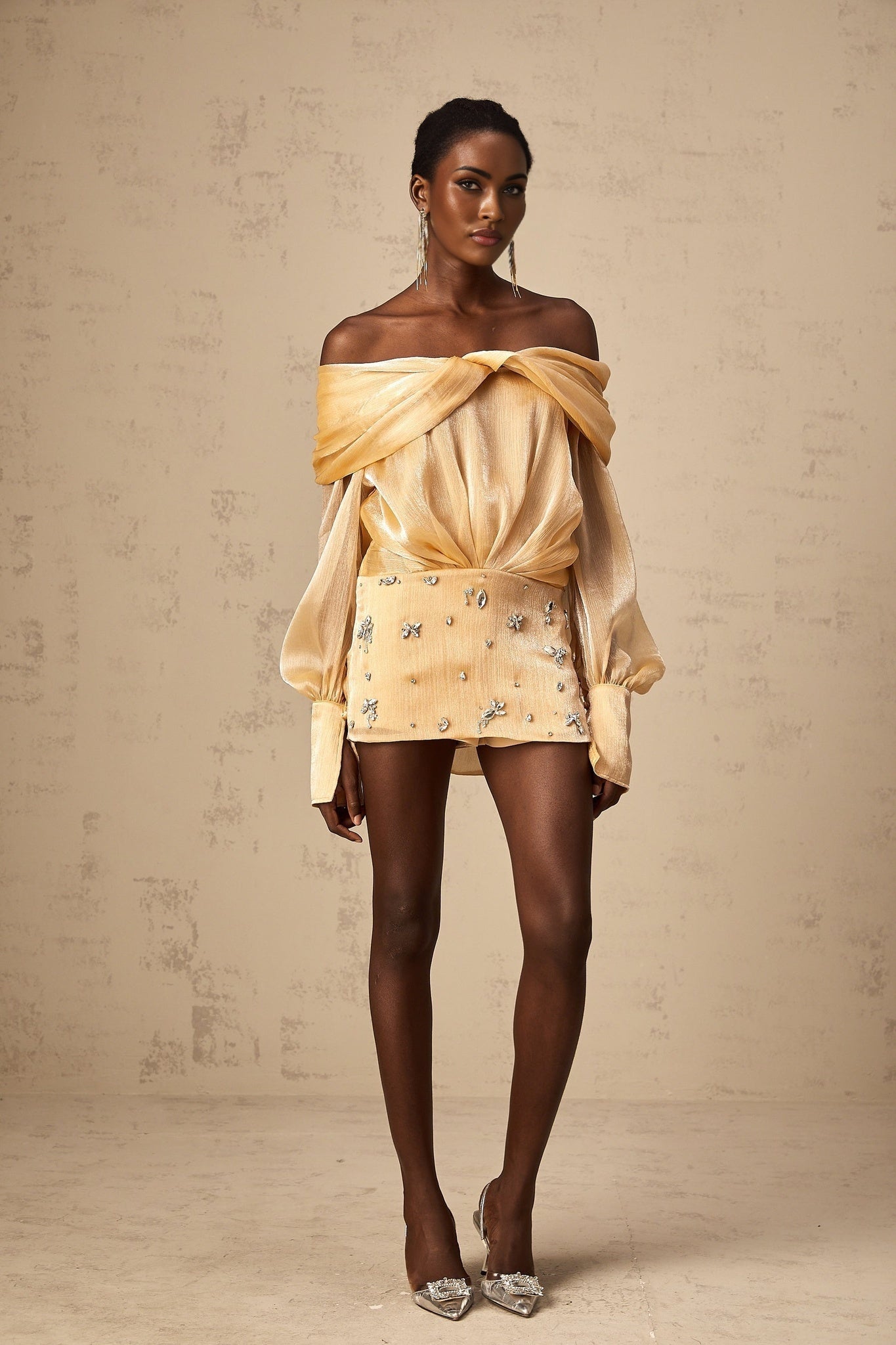 A short gold mini dress with crystal embellishments and paneled design featuring a sleeveless silhouette and formfitting shape