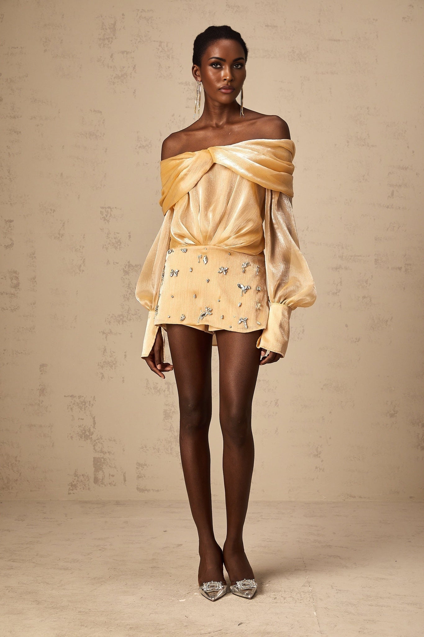 A short gold mini dress with crystal embellishments and paneled design featuring a sleeveless silhouette and shimmering fabric