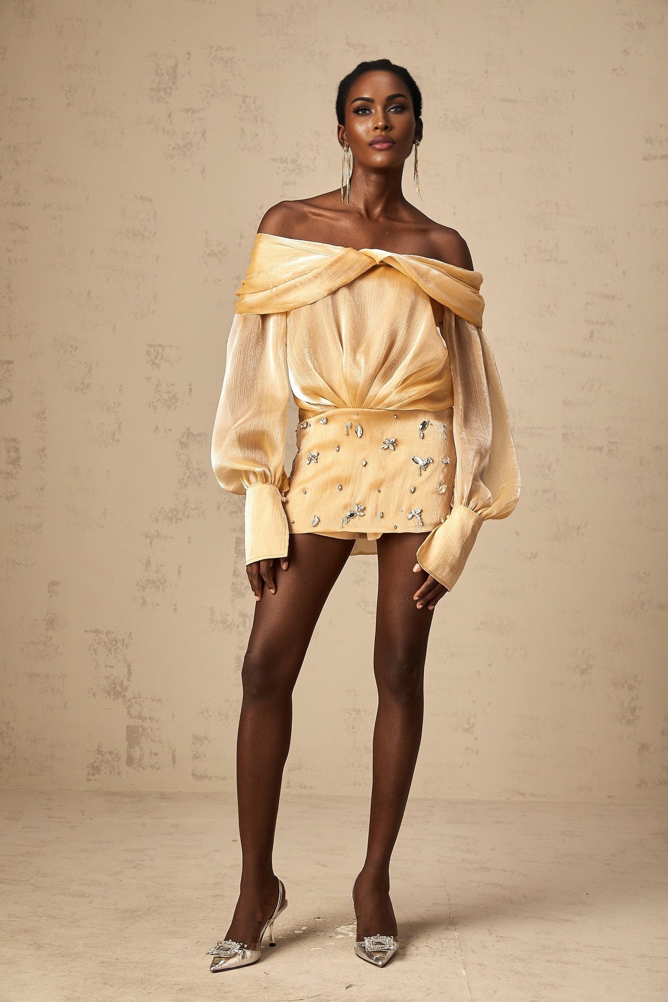 A short gold mini dress with crystal embellishments and paneled design featuring a sleeveless silhouette and shimmering fabric