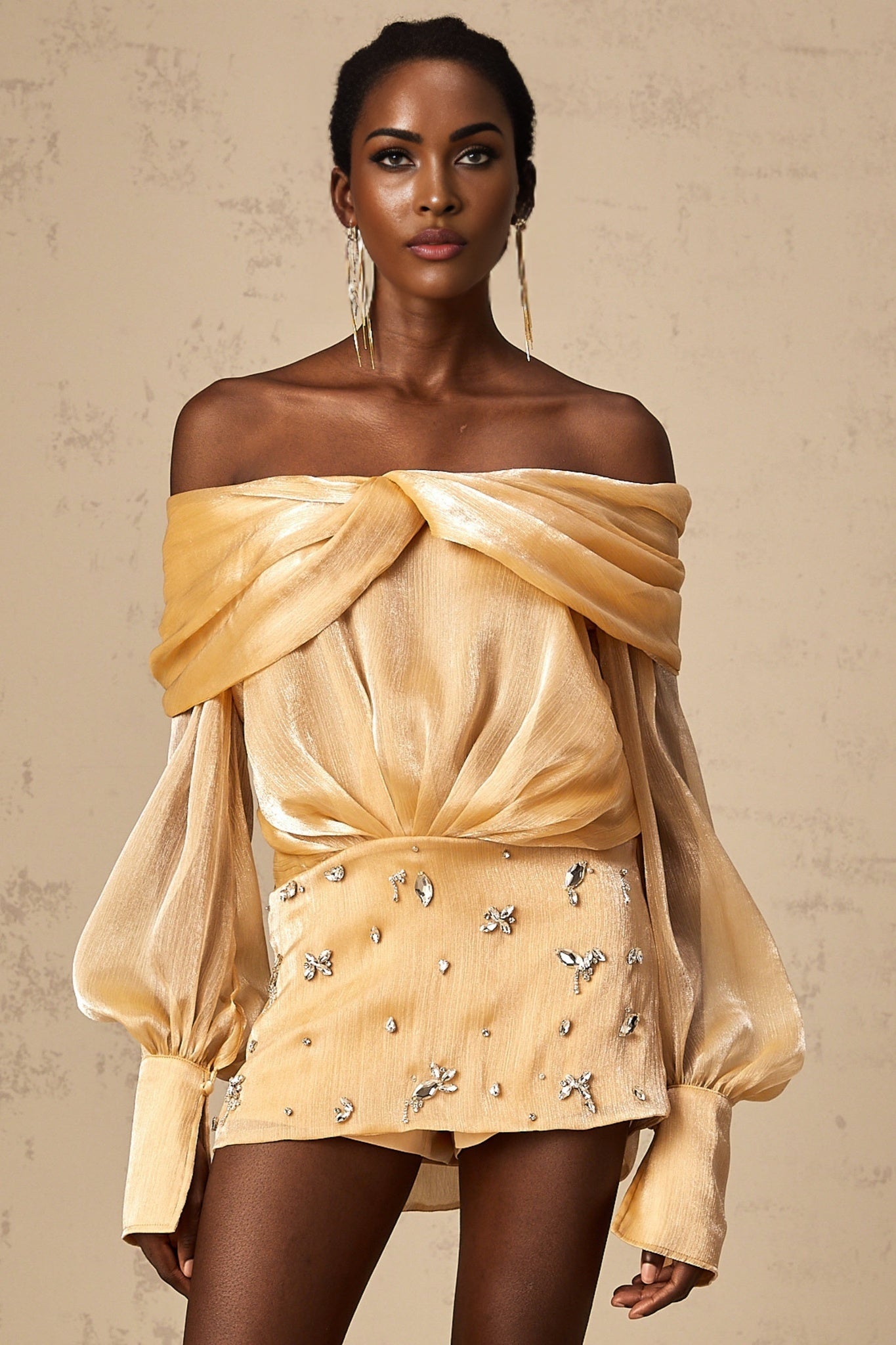 A short gold mini dress with crystal embellishments and panelled design featuring a sleek silhouette and shimmering details