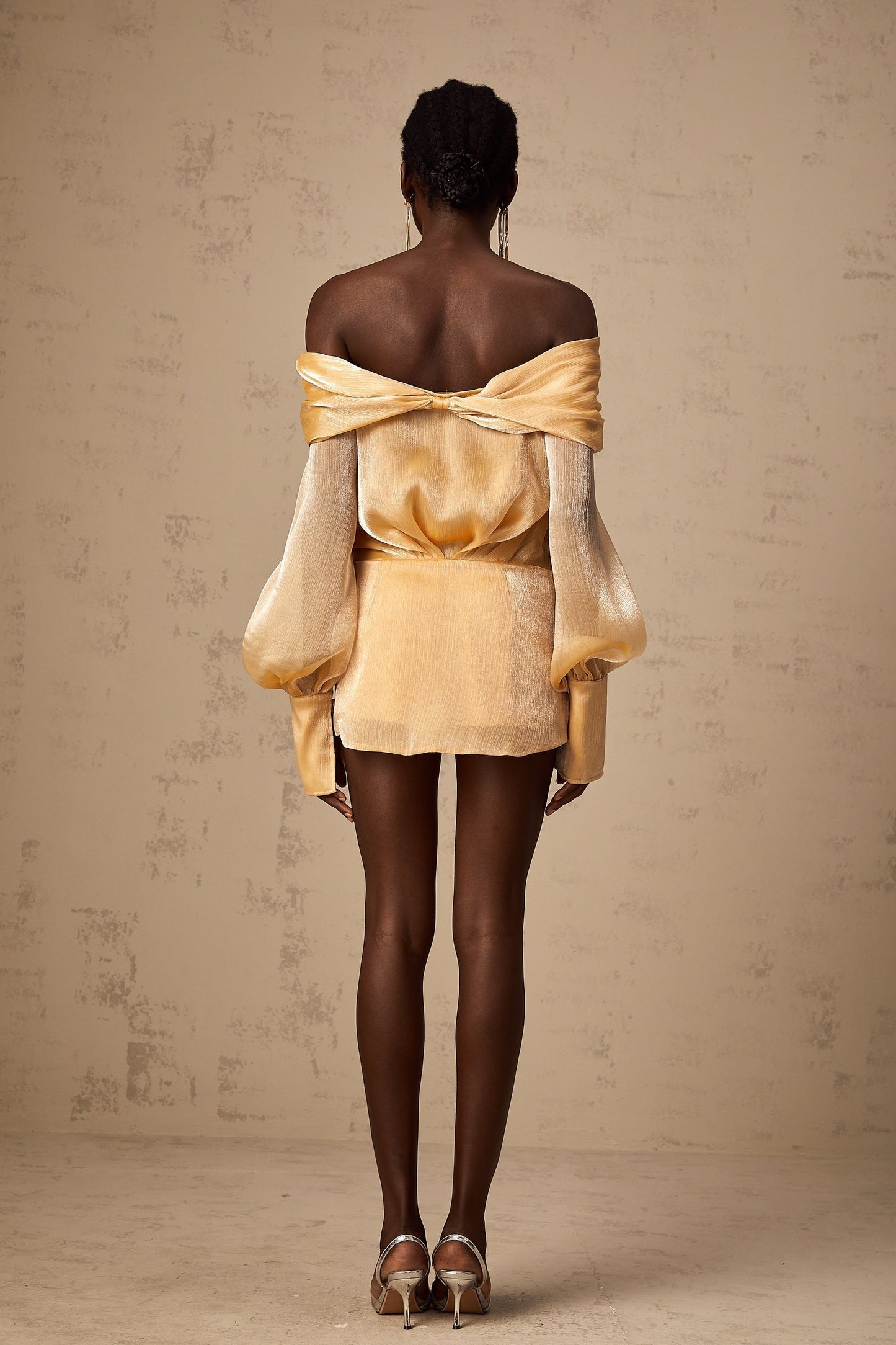 A short gold mini dress with crystal embellishments and panelled design featuring a sleeveless silhouette and shimmering fabric