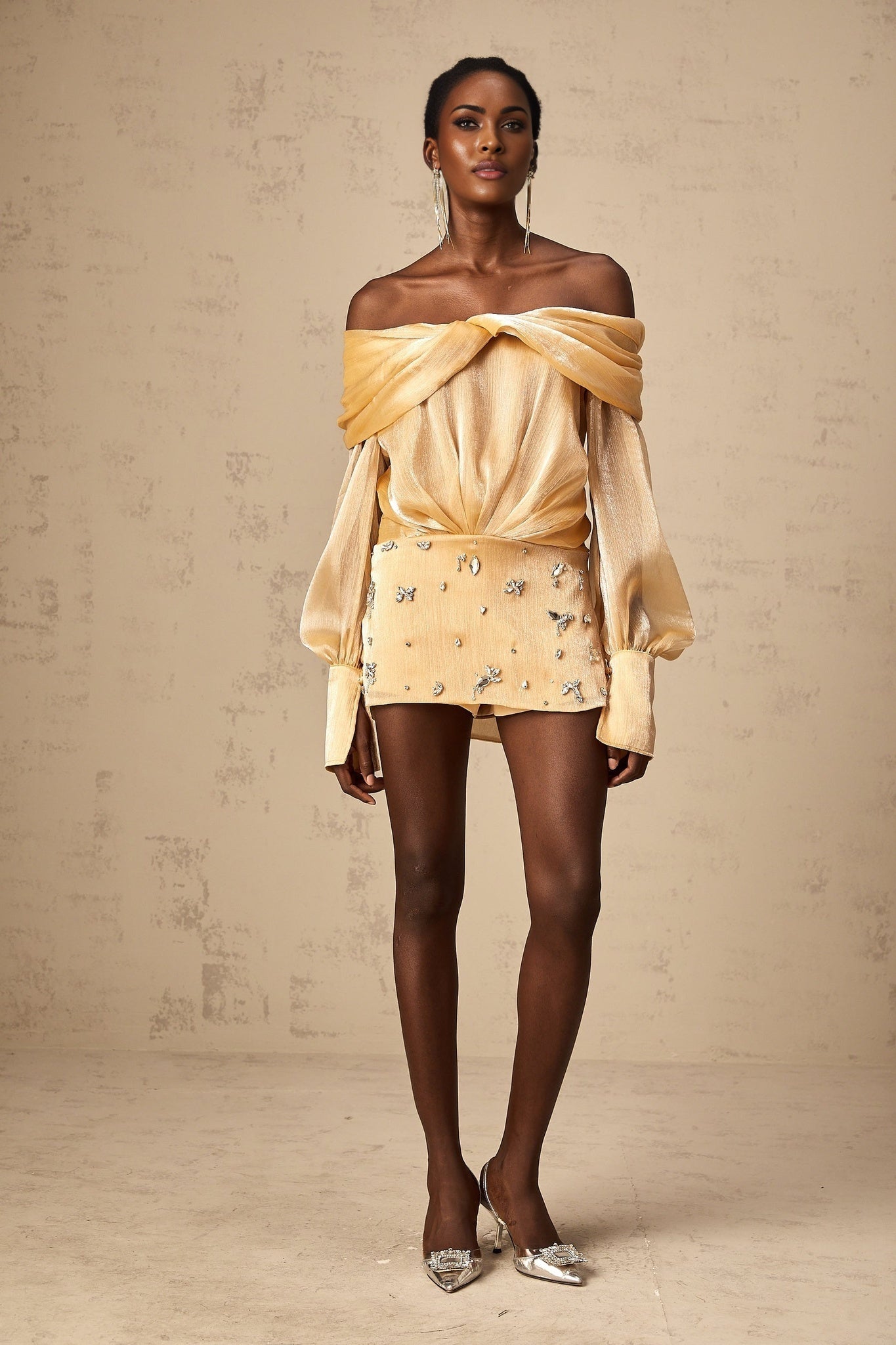 A short gold mini dress with crystal embellishments and panelled design featuring a sleeveless silhouette and shimmering fabric