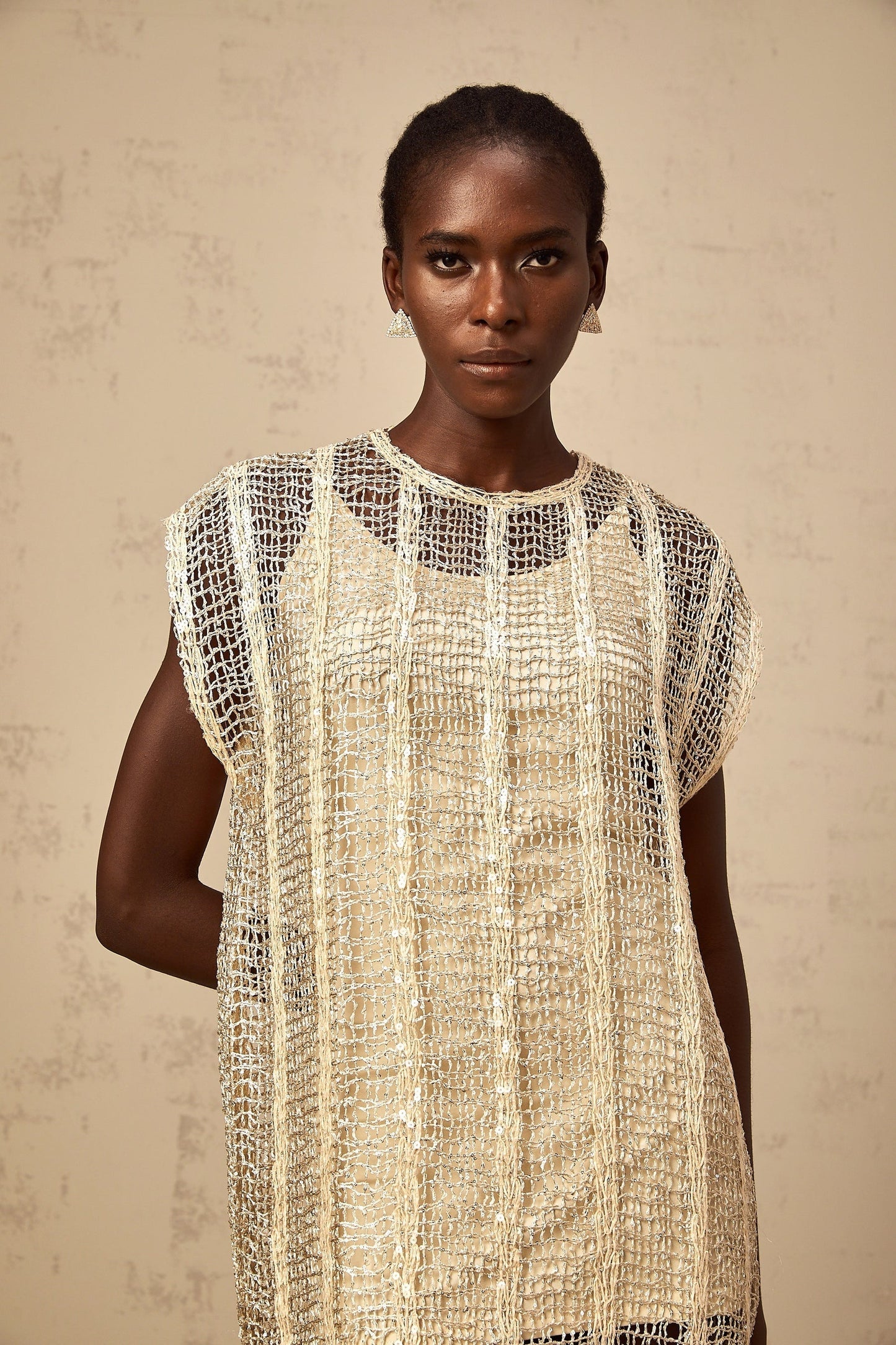 A short gold mini dress with sequin embellishments and cut out details on a model