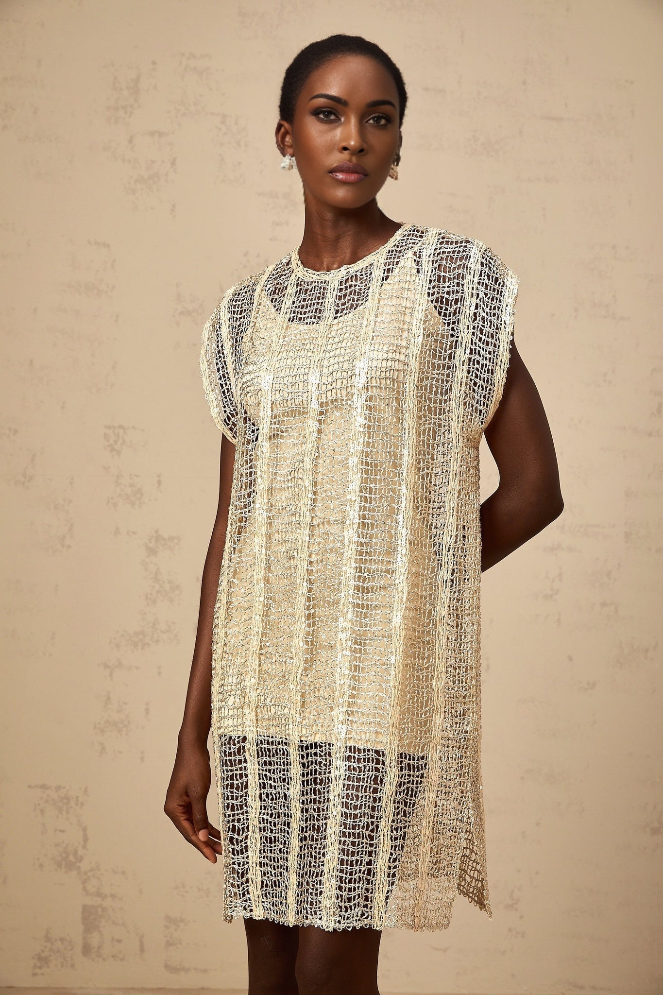 A short gold mini dress with sequin embellishments and cut out details worn by a model