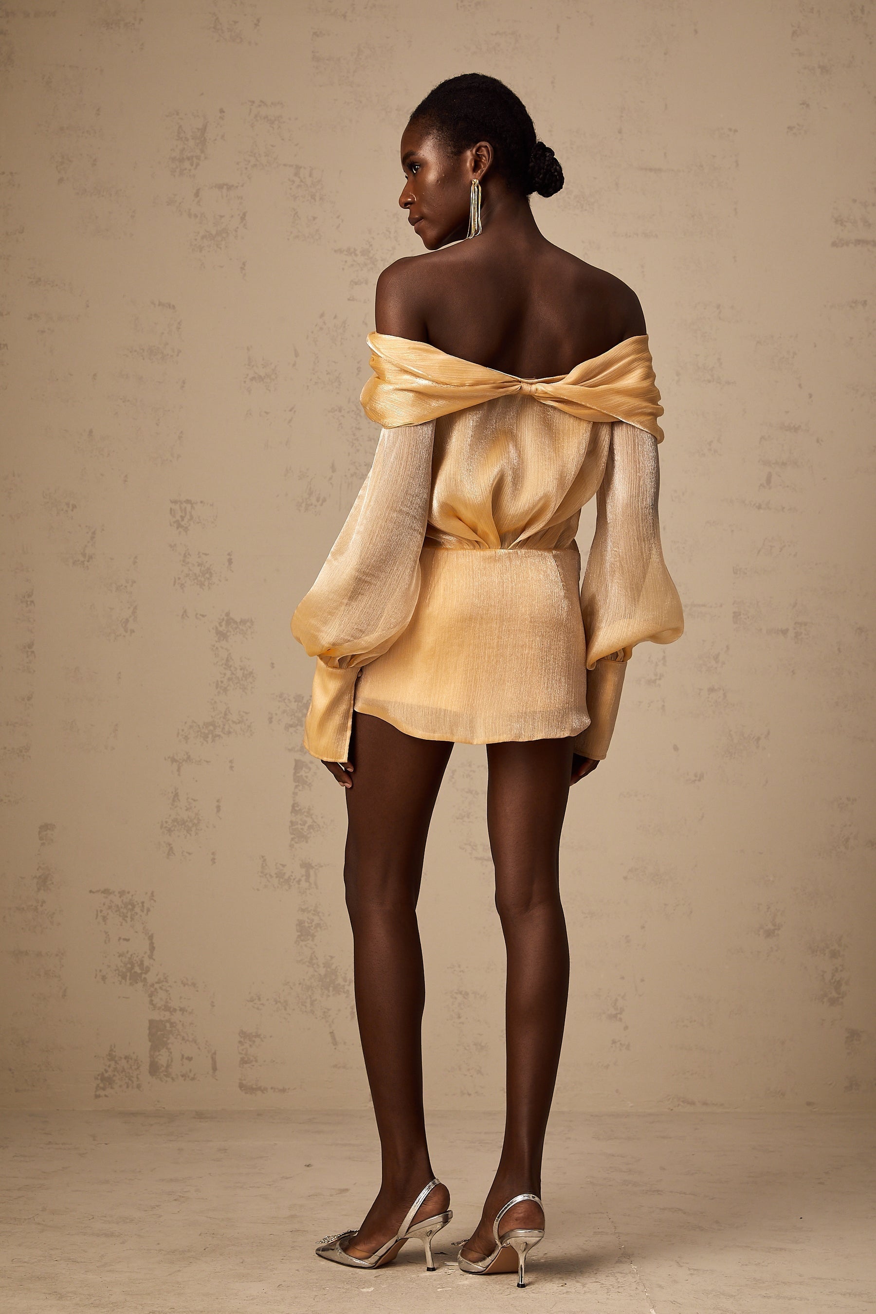 A short golden dress with crystal embellishments and paneled design featuring a mini length and shimmering fabric