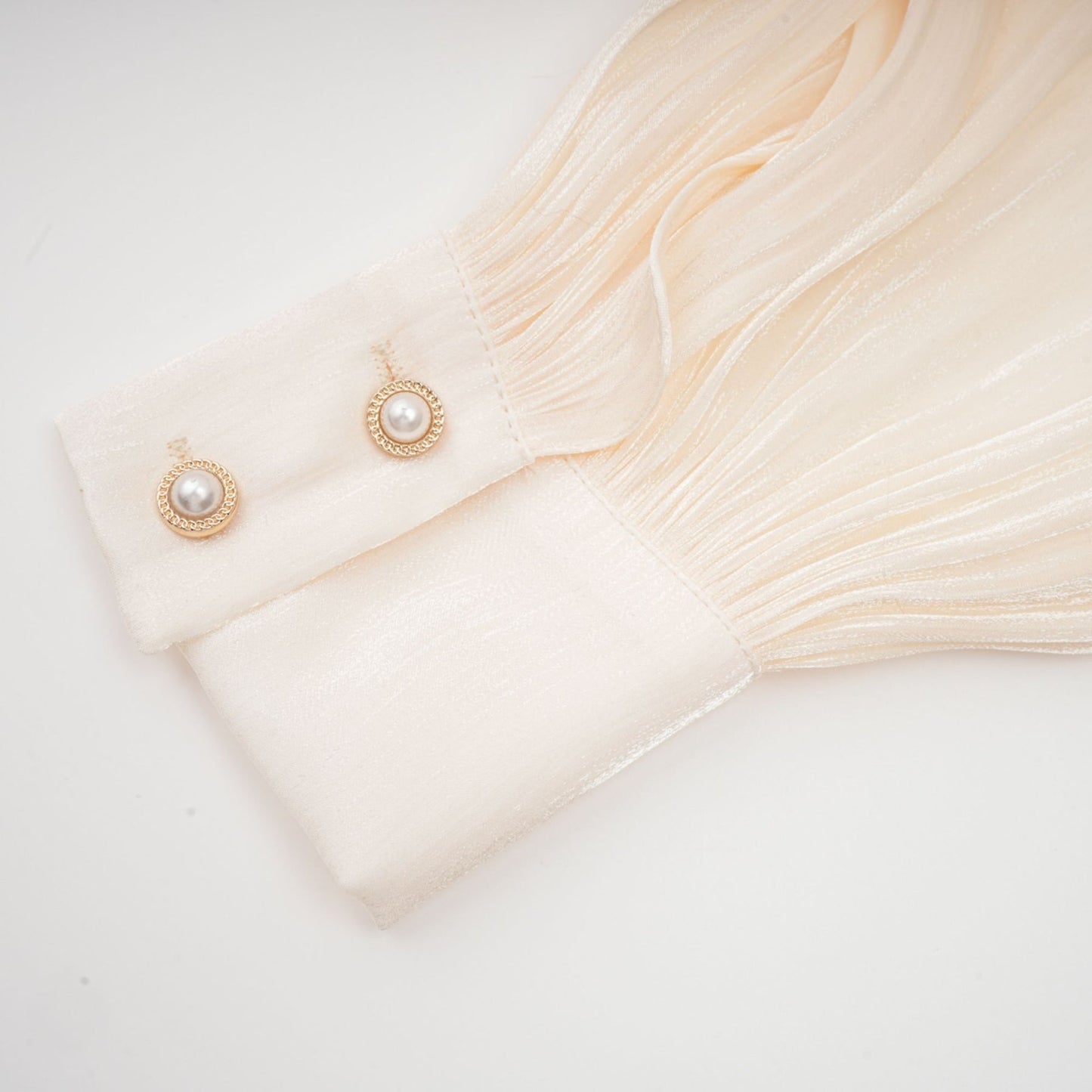 A short neutralcolored mini dress with full pleats and ruffles named Eugénie