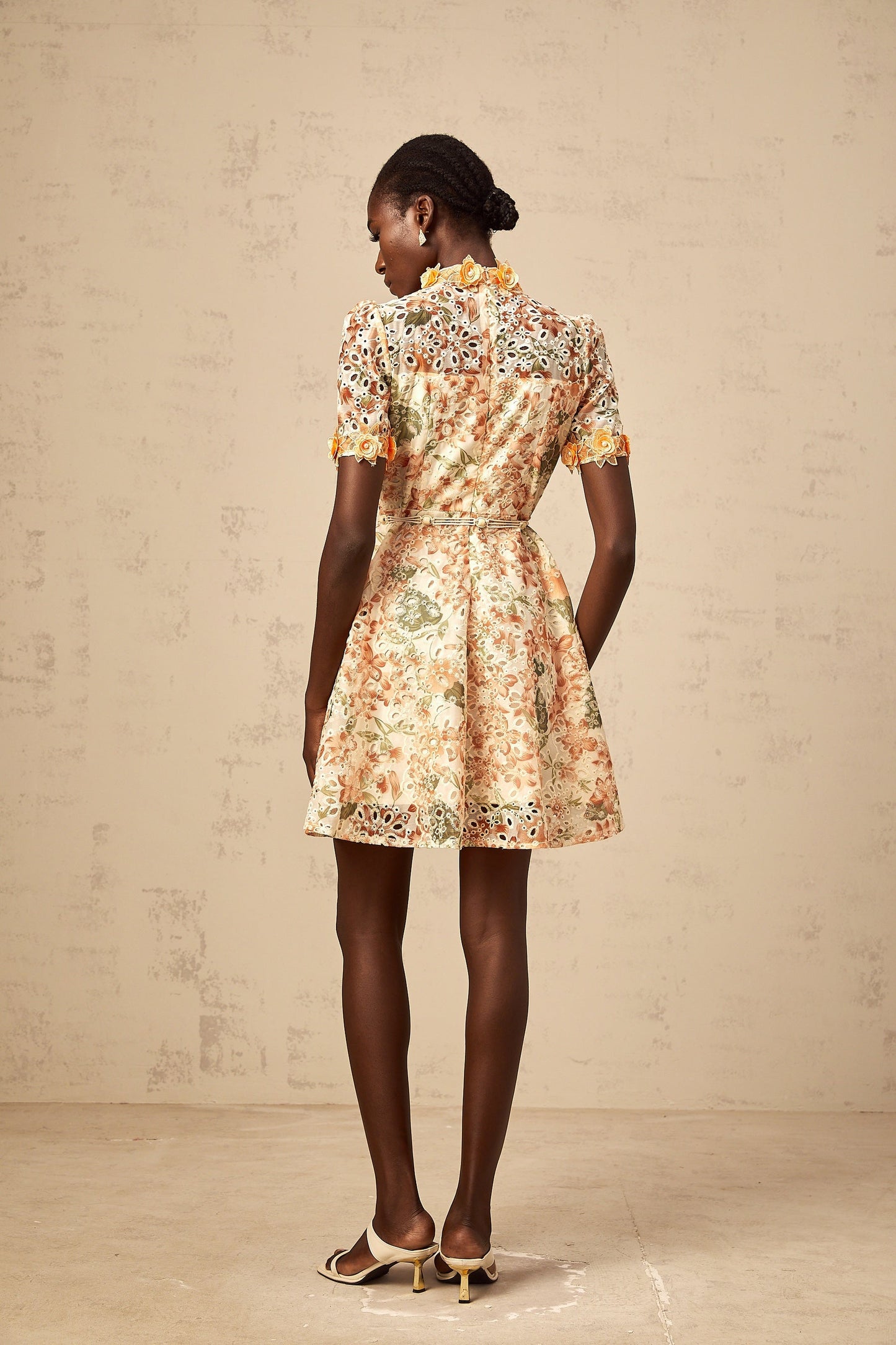 A short orange mini dress with floral embroidery and embellishments featuring a fitted silhouette and delicate flower designs stitched onto the fabric