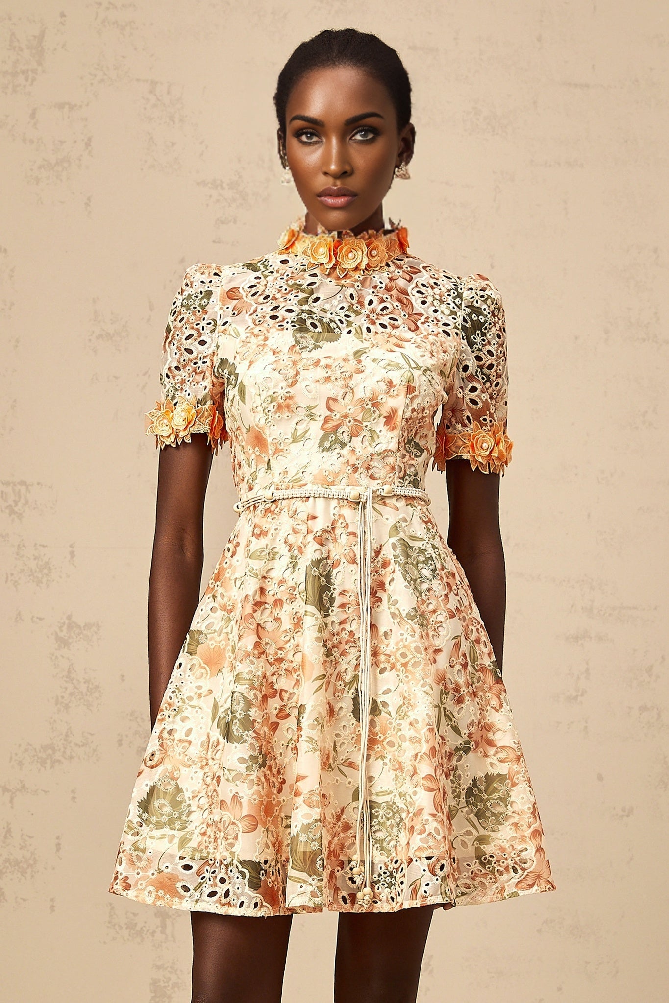 A short orange mini dress with floral embroidery and embellishments featuring a fitted silhouette and delicate flower patterns
