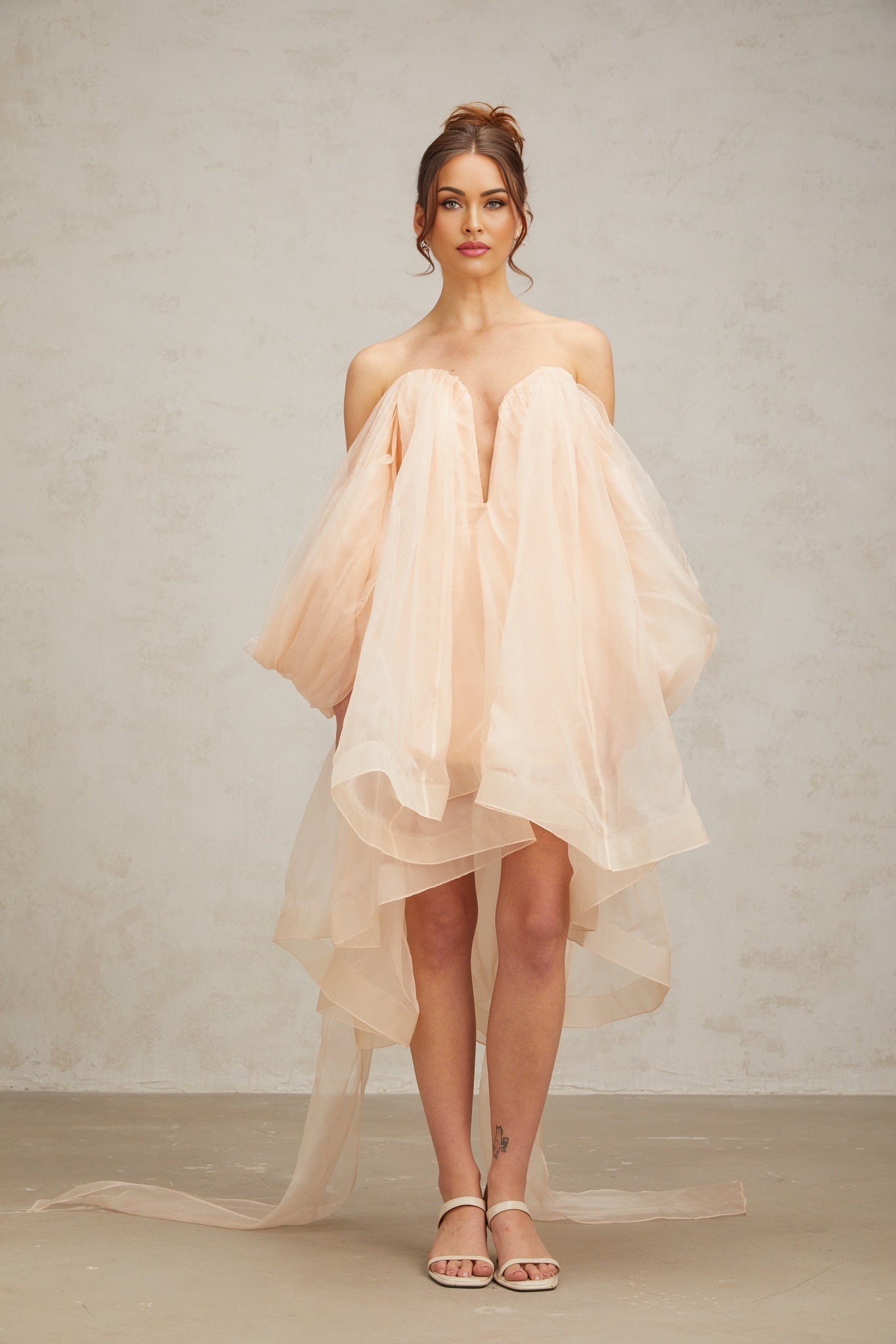A short pastel pink mini dress with voluminous sleeves and a large bow detail at the neckline