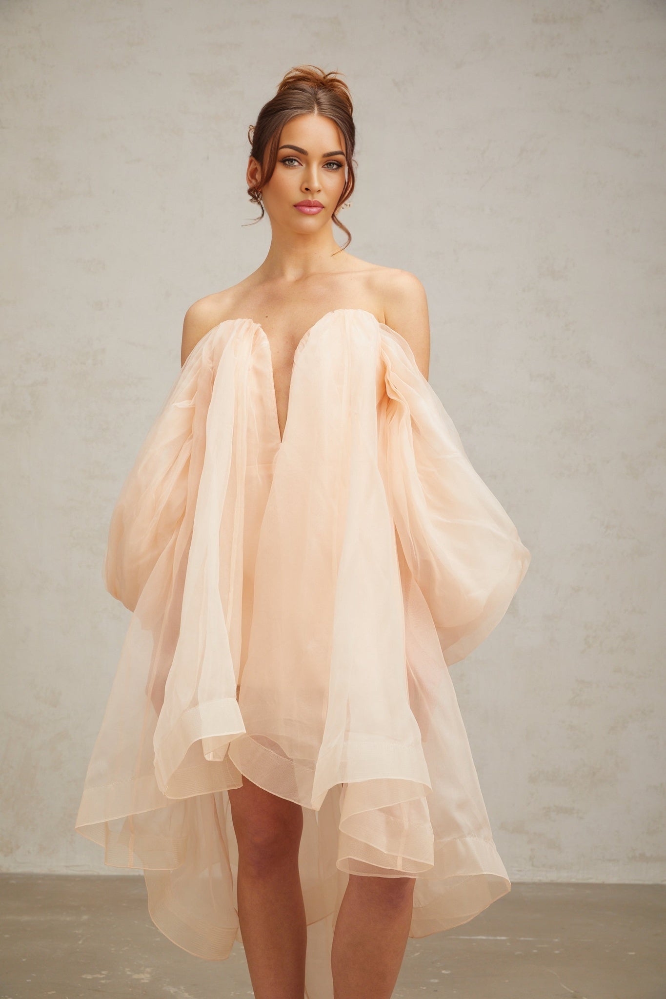 A short pink mini dress with voluminous sleeves and a large bow detail at the front neckline