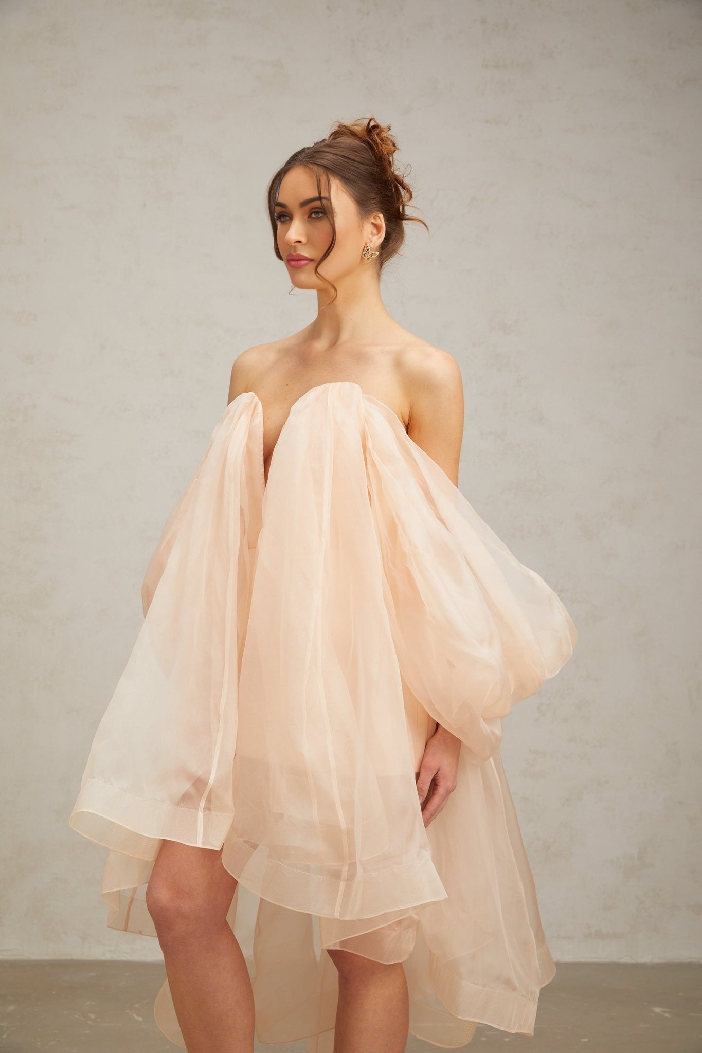 A short pink mini dress with voluminous sleeves and a large bow detail at the neckline