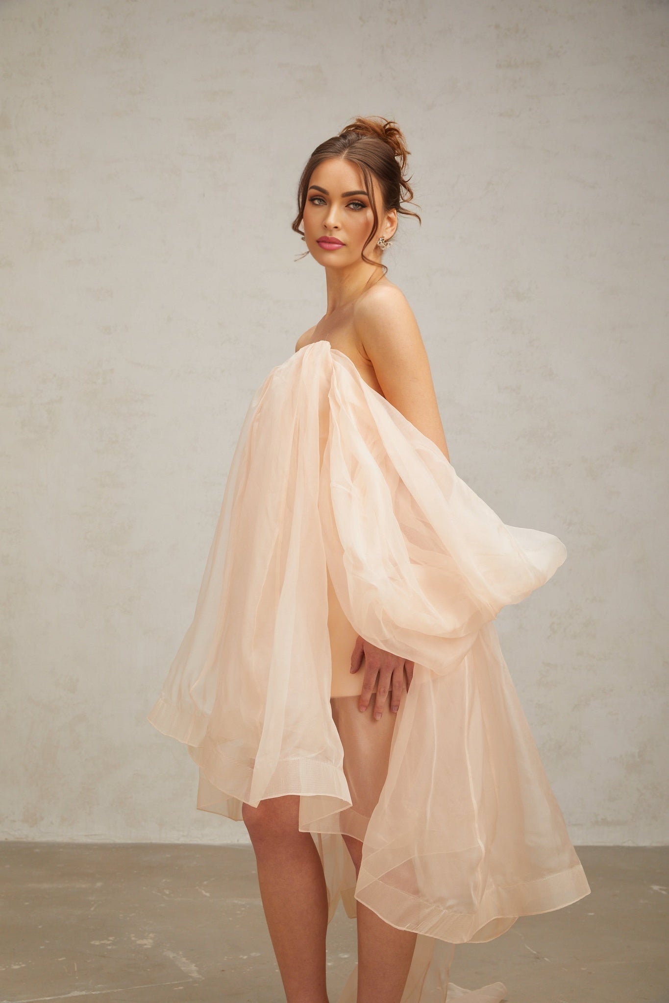 A short pink mini dress with voluminous sleeves and a large bow detail at the neckline
