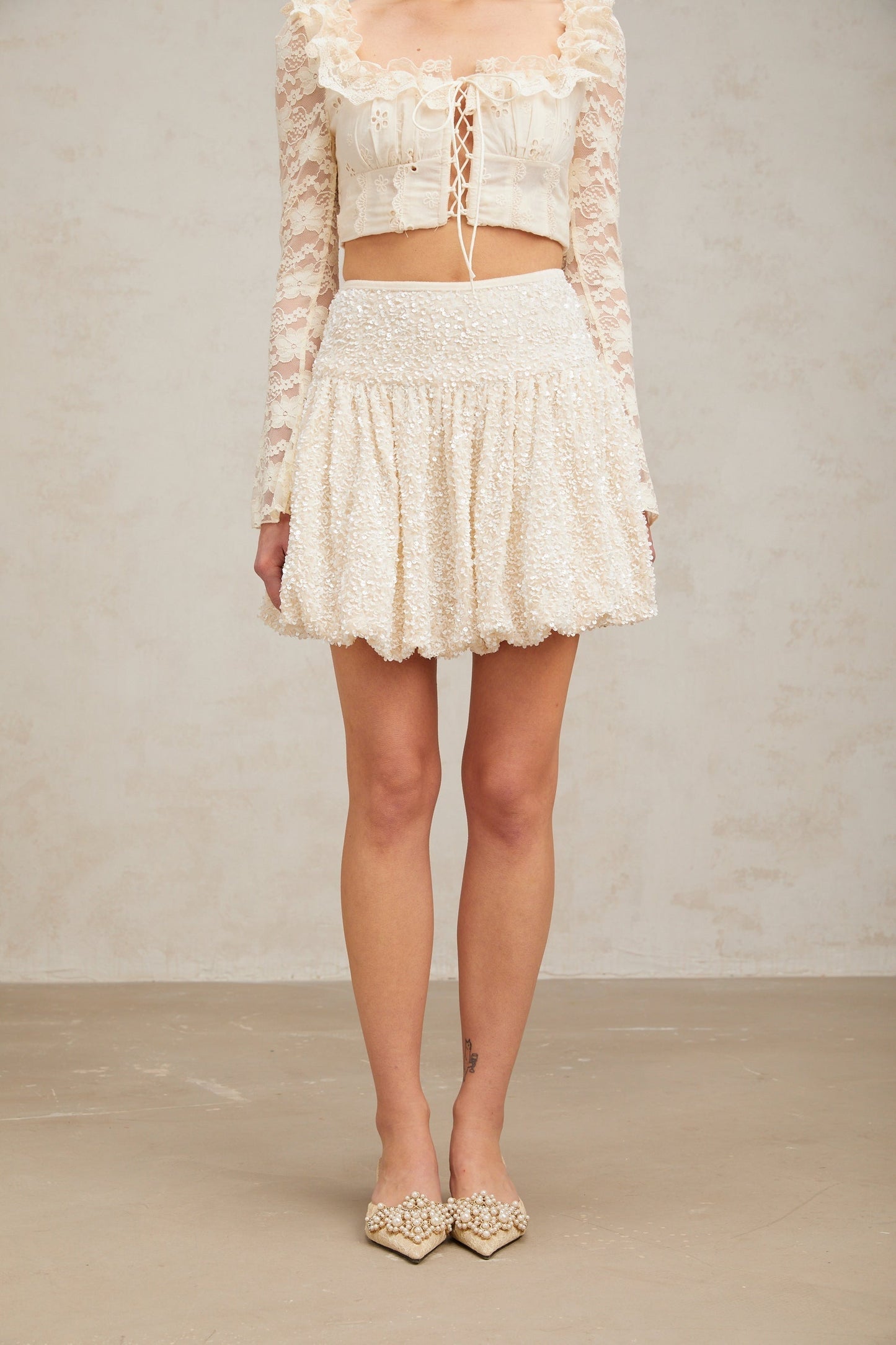 A short pleated mini skirt with sequin embellishments called Tiphaine