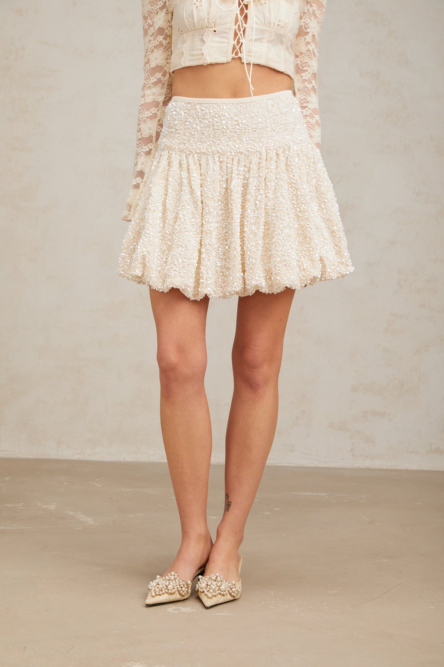 A short pleated mini skirt with shimmering sequins covering the fabric creating a sparkling effect