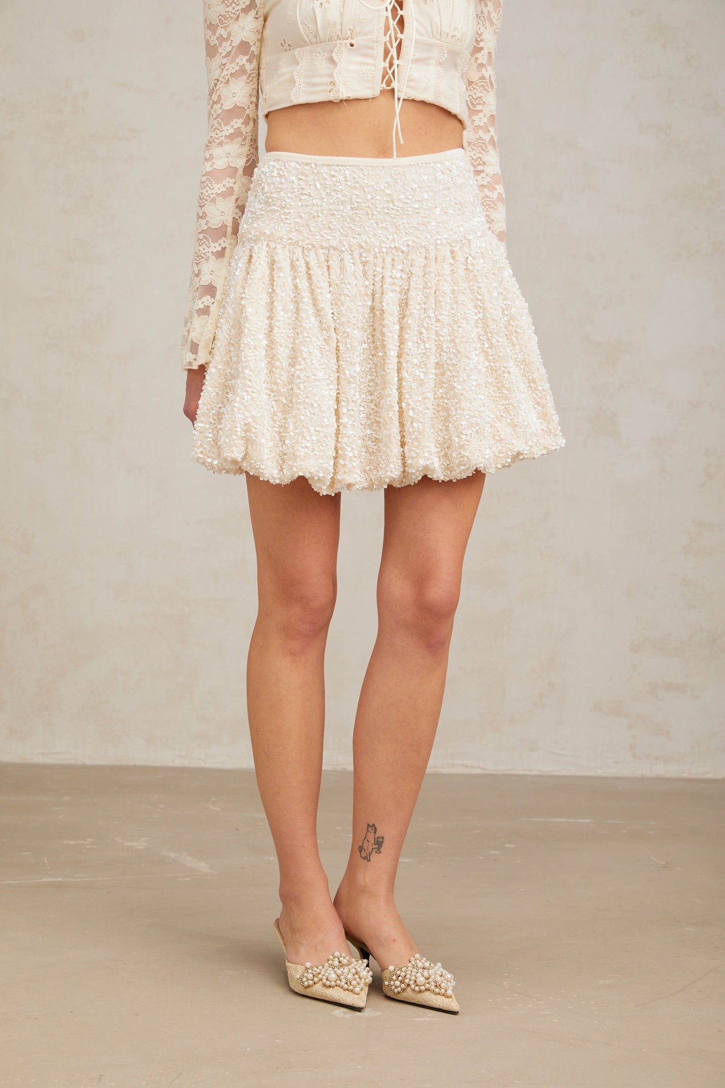 A short pleated mini skirt with shimmering sequins covering the fabric creating a sparkly and festive look