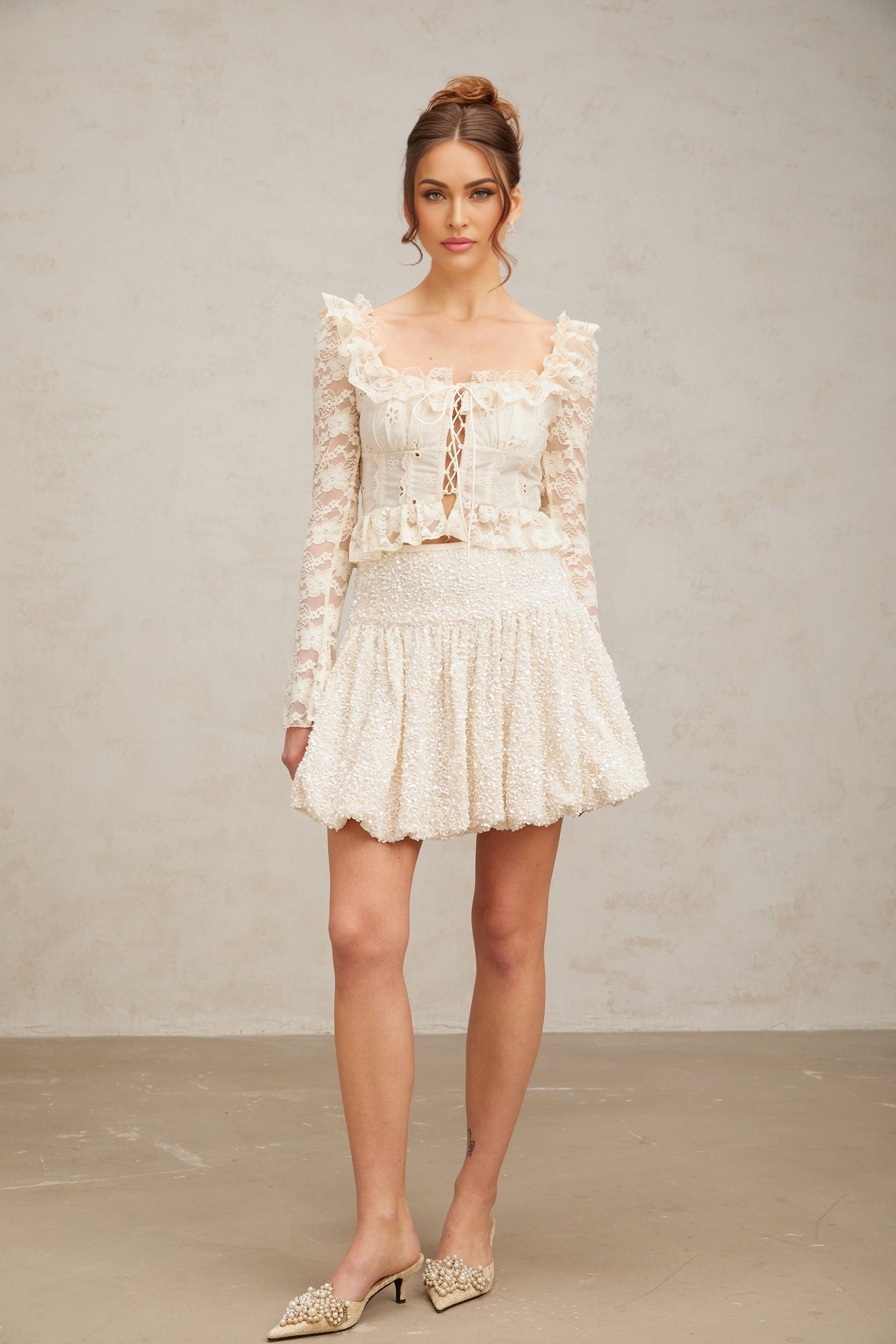 A short pleated mini skirt with sparkling sequins covering the fabric named Tiphaine