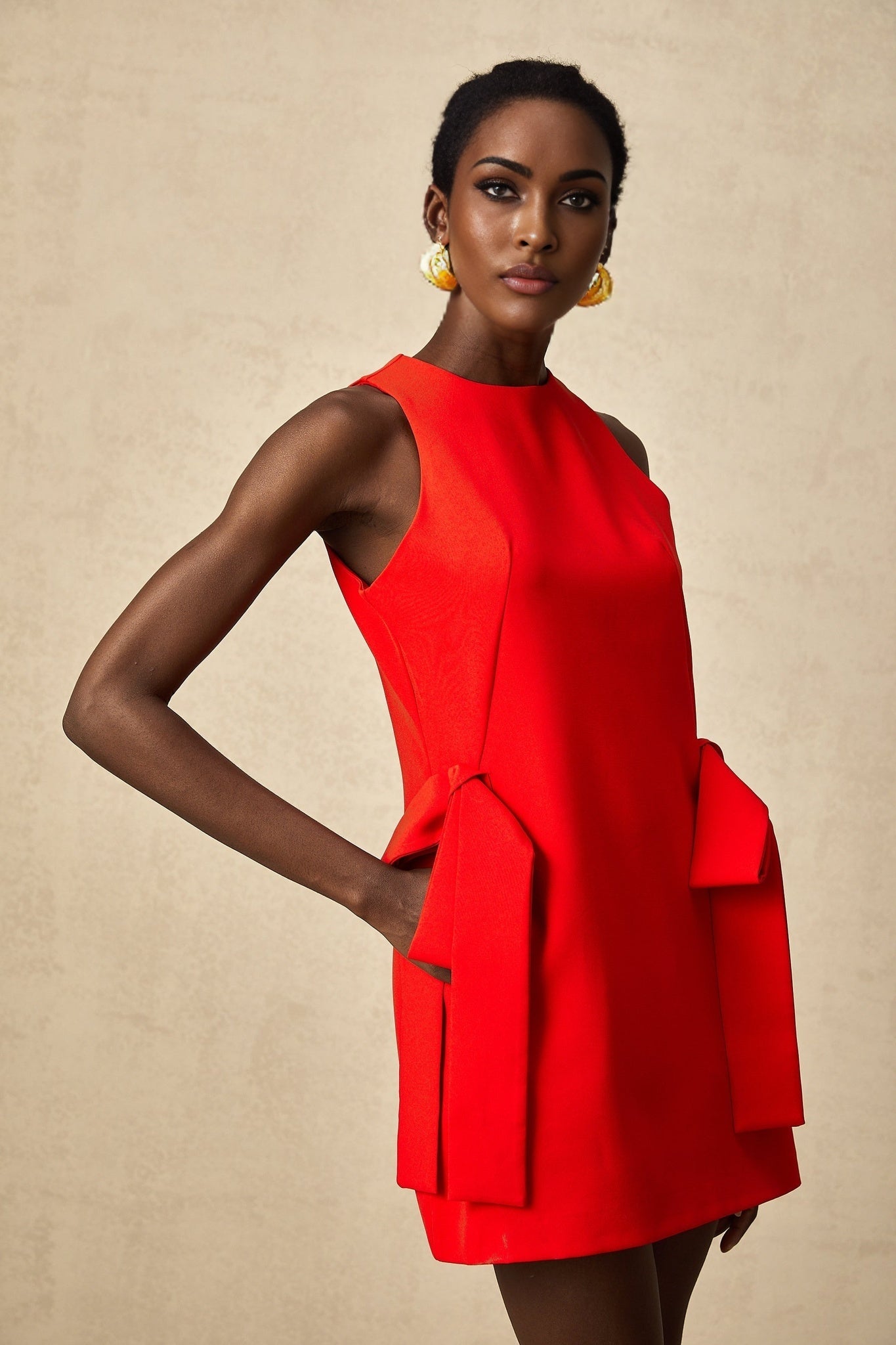 A short red sleeveless mini dress with a bow detail