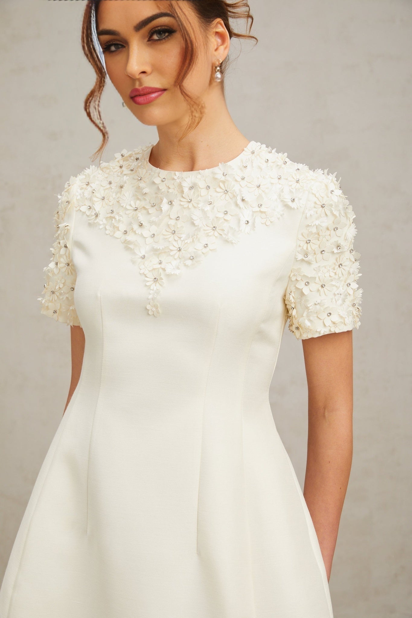 A short sleeveless dress with colorful floral applique details on a light background showcasing the Adrienne mini dress design