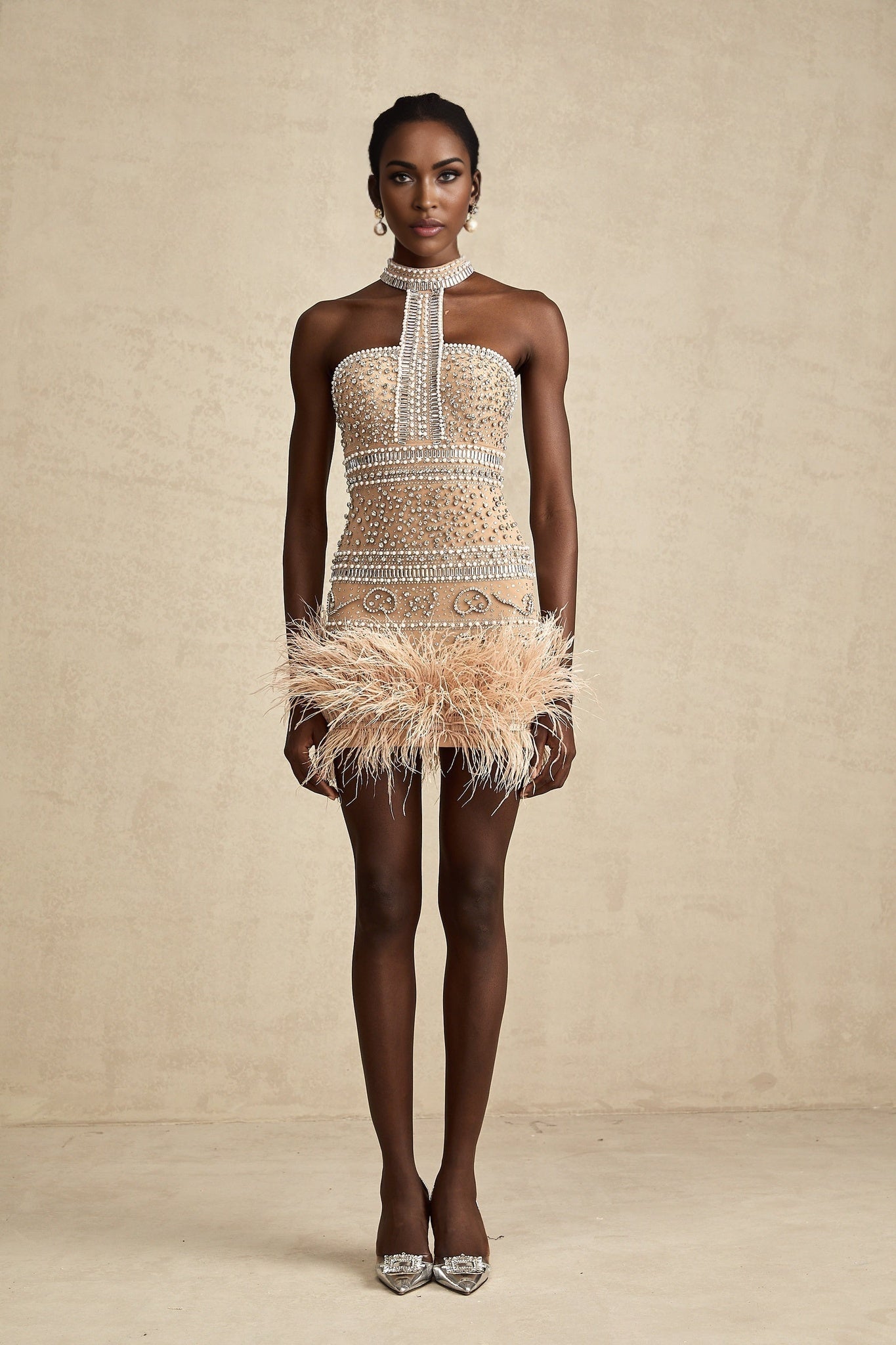 A short sleeveless mini dress adorned with crystal embellishments and featuring a feather trim along the hemline