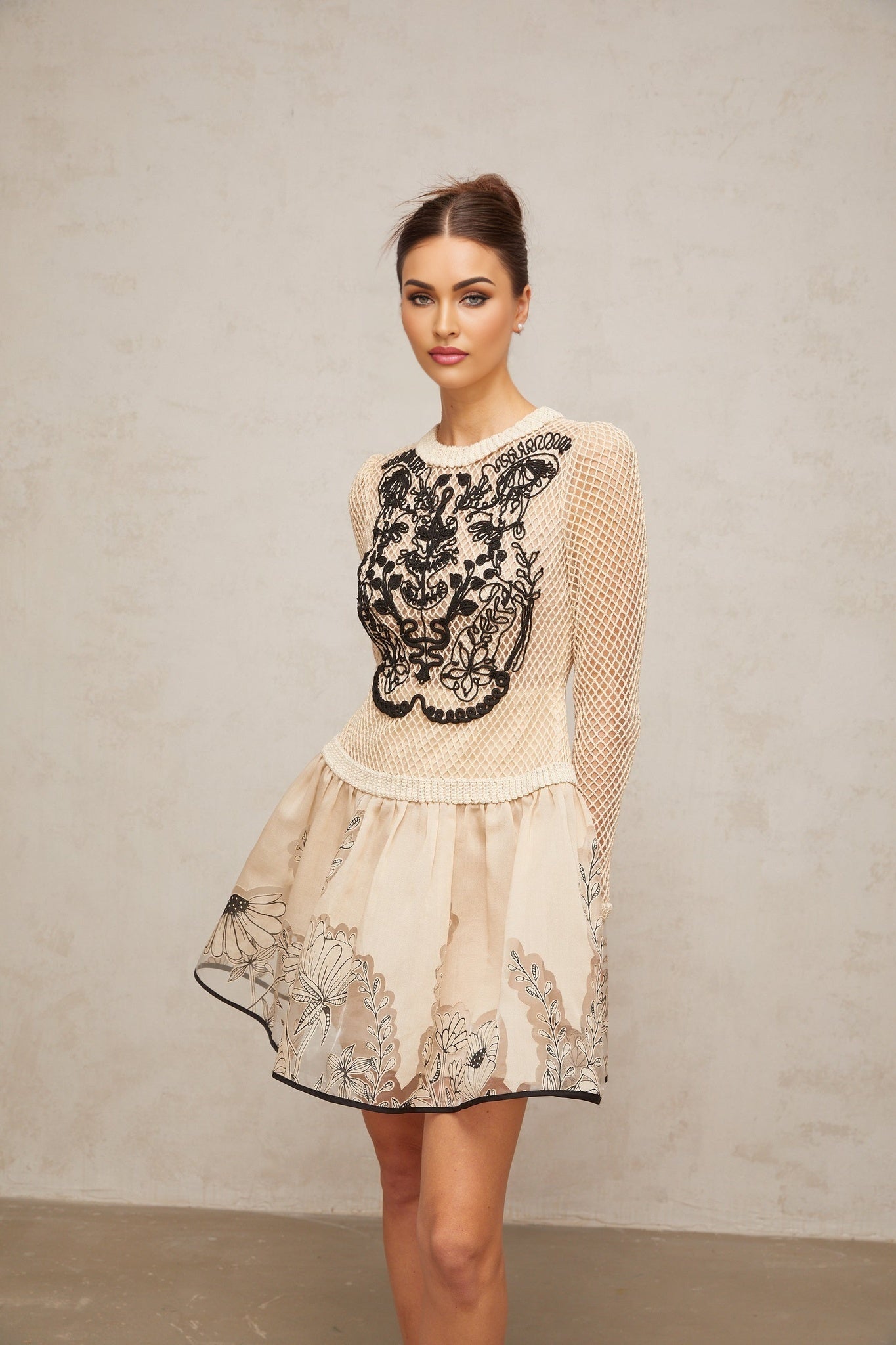 A short sleeveless mini dress with a floral jacquard pattern featuring contrasting color floral appliques and a fitted silhouette