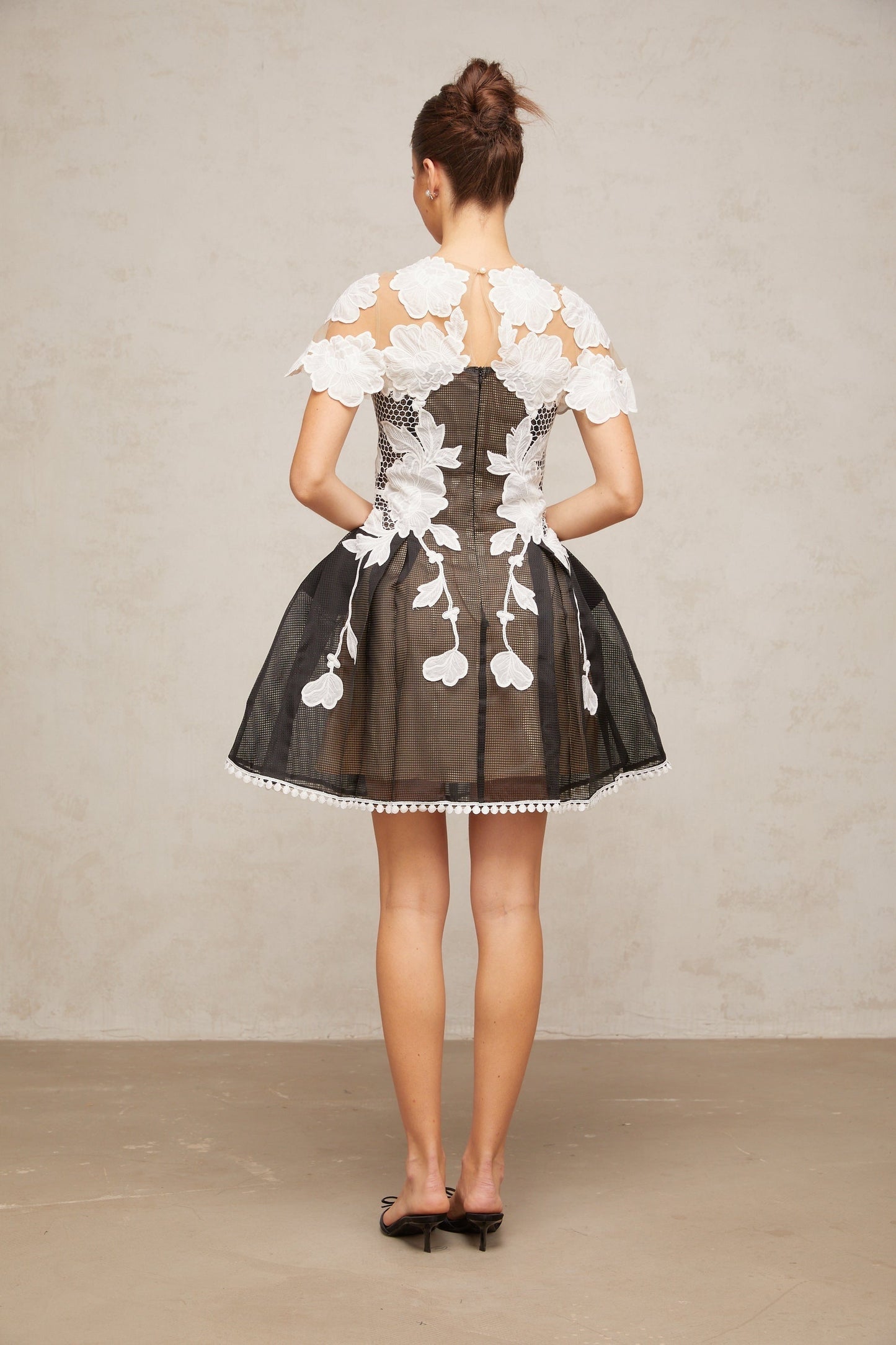 A short sleeveless mini dress with colorblocked sections featuring floral embroidery designs in contrasting colors creating a vibrant and feminine look