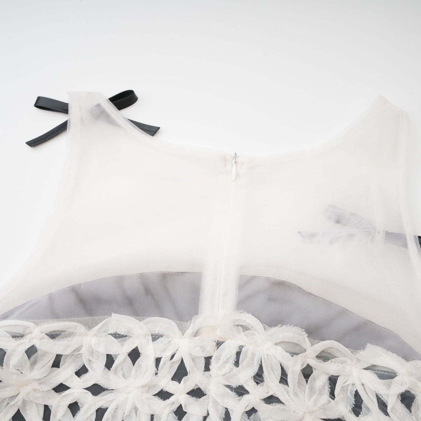 Monochrome dress without sleeves featuring a bow braided pattern and partial transparency Back zipper and thighlength Made of 67% cotton 33% polyester