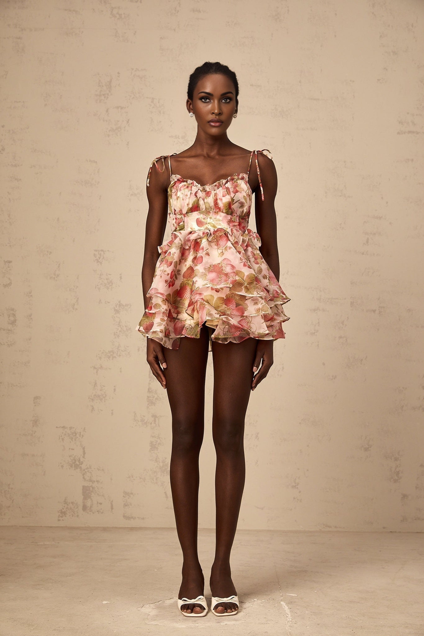 A short tiered mini dress with a strawberry print pattern covering the fabric The dress features a feminine design with ruffled layers and a summery look
