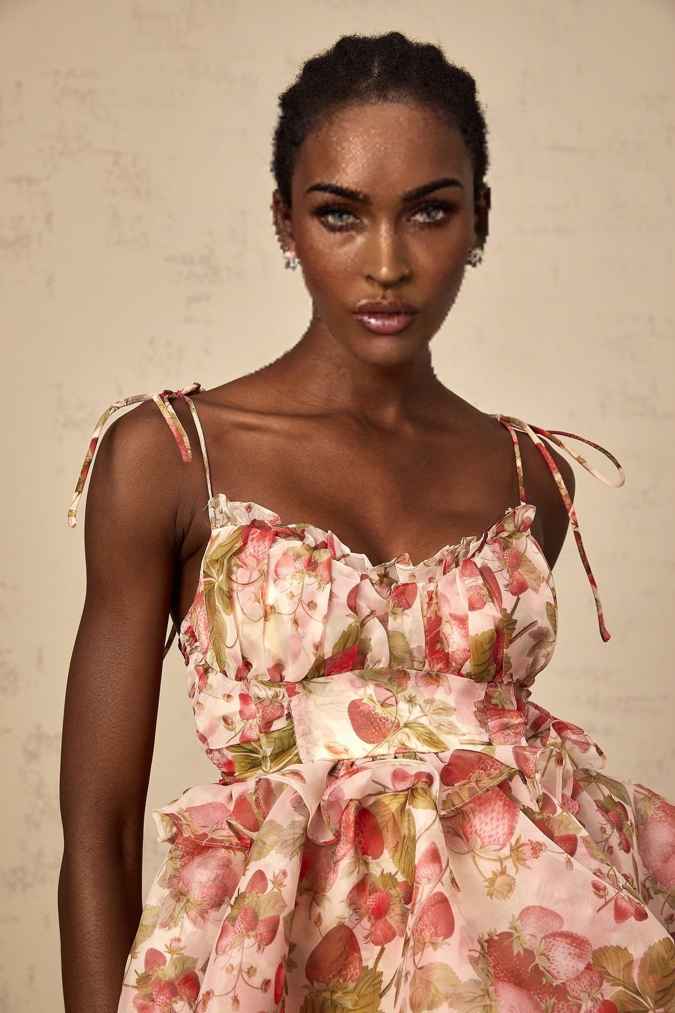 A short tiered mini dress with a strawberry print pattern featuring ruffled layers and a feminine silhouette