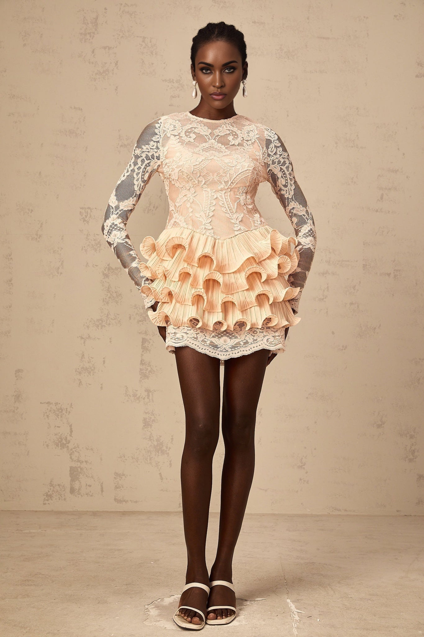 A short tiered mini dress with floral lace panels worn by a model against a plain background The dress features a feminine design with a mix of solid fabric and delicate lace detailing