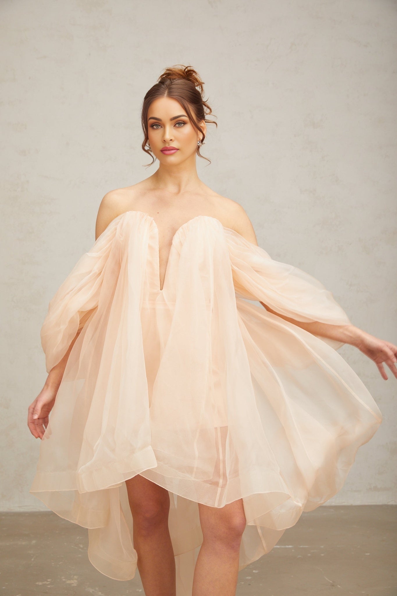A short white dress with voluminous sleeves and a large bow detail at the neckline