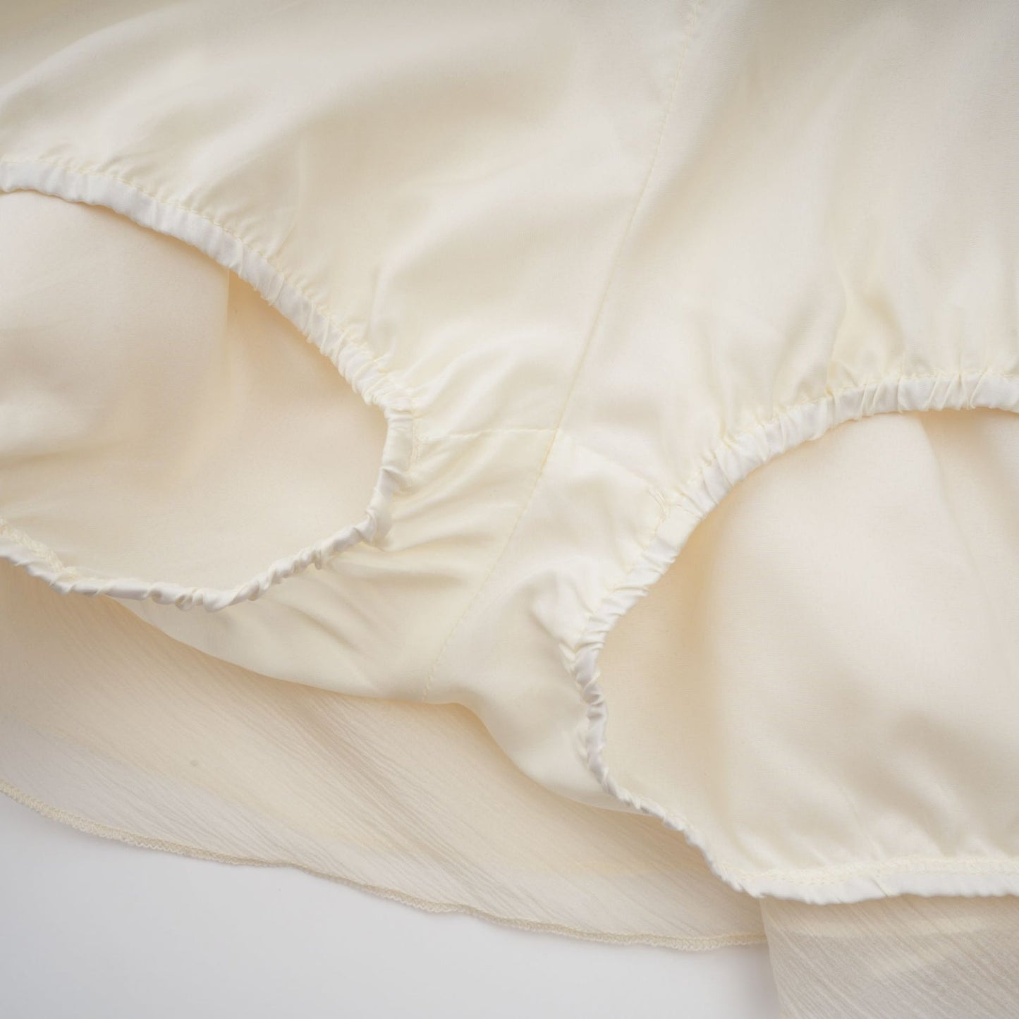 A short white halterneck mini dress with faux pearl embellishments on a mannequin or model against a plain background