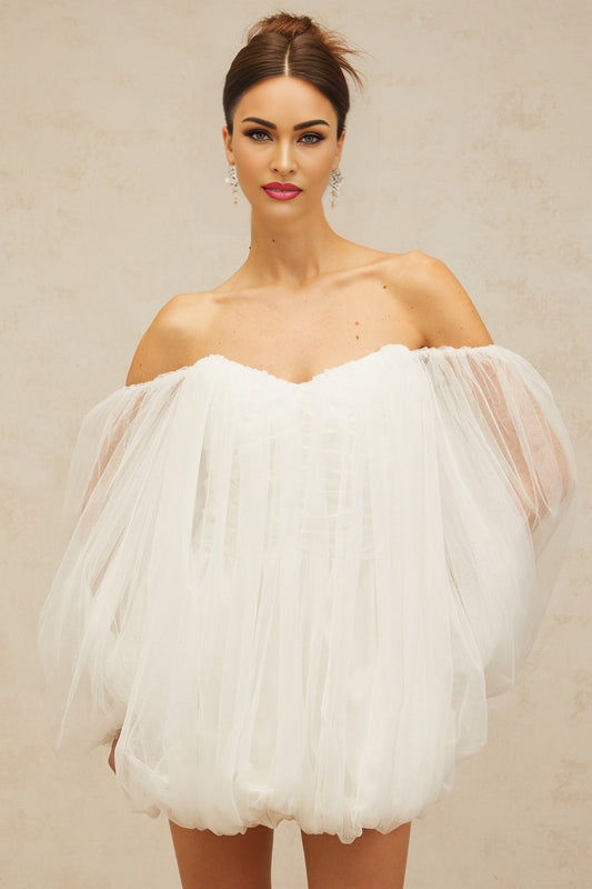 A short white layered dress with a puffy tulle skirt and bubblelike texture worn by a model against a plain background